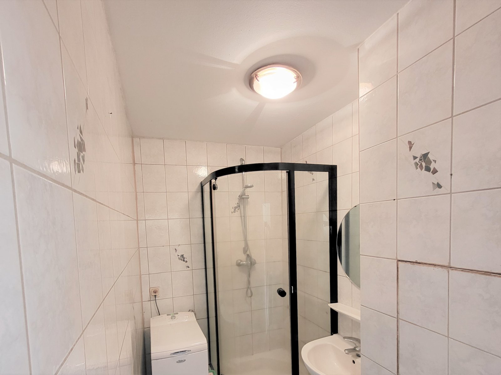 Koupelna se sprchovým koutem, pračkou a toaletou