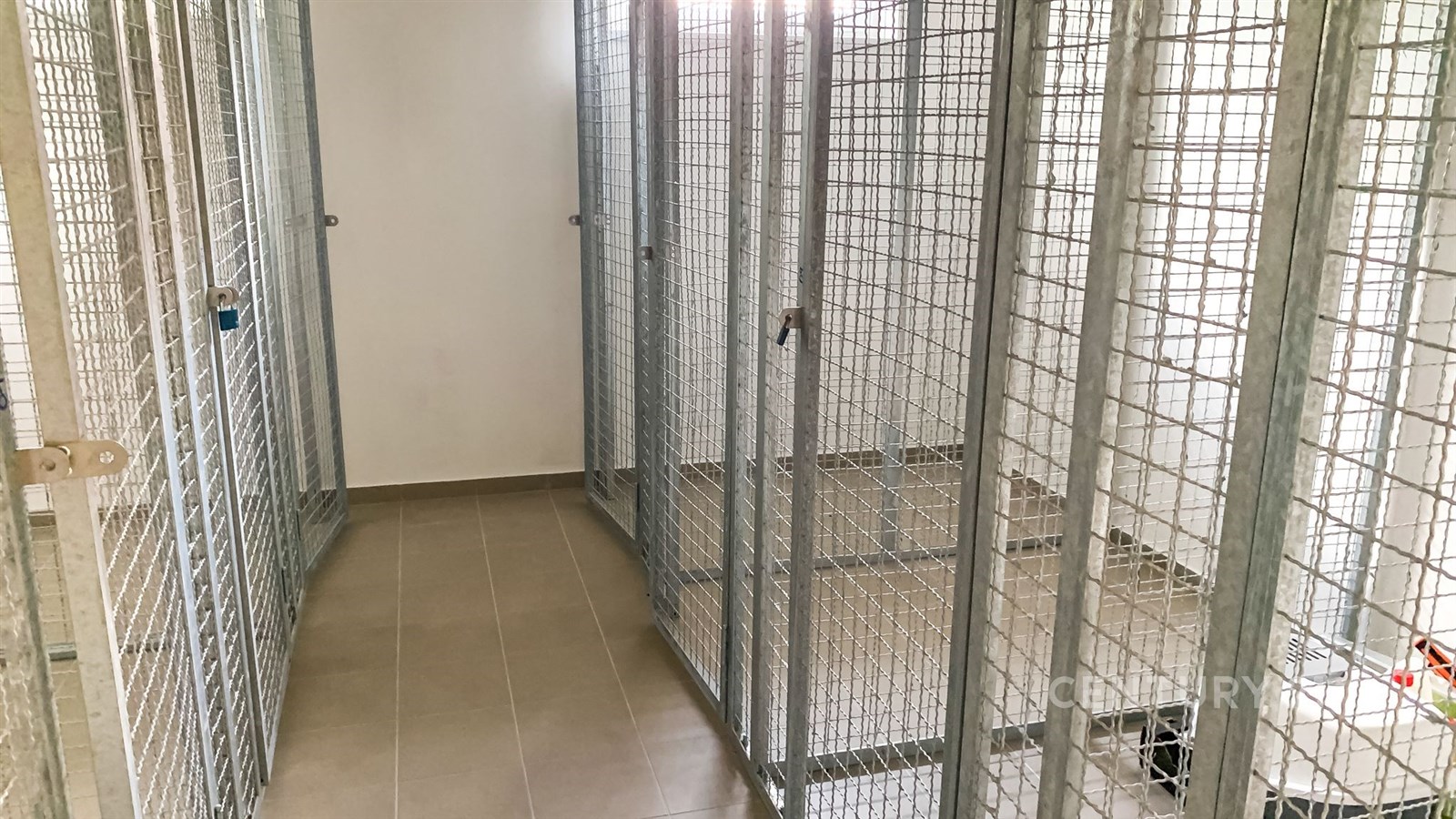 Prázdné místnosti se železnými klecemi, dlažba na podlaze, jednoduché bílé stěny, vhodné pro skladovací využití