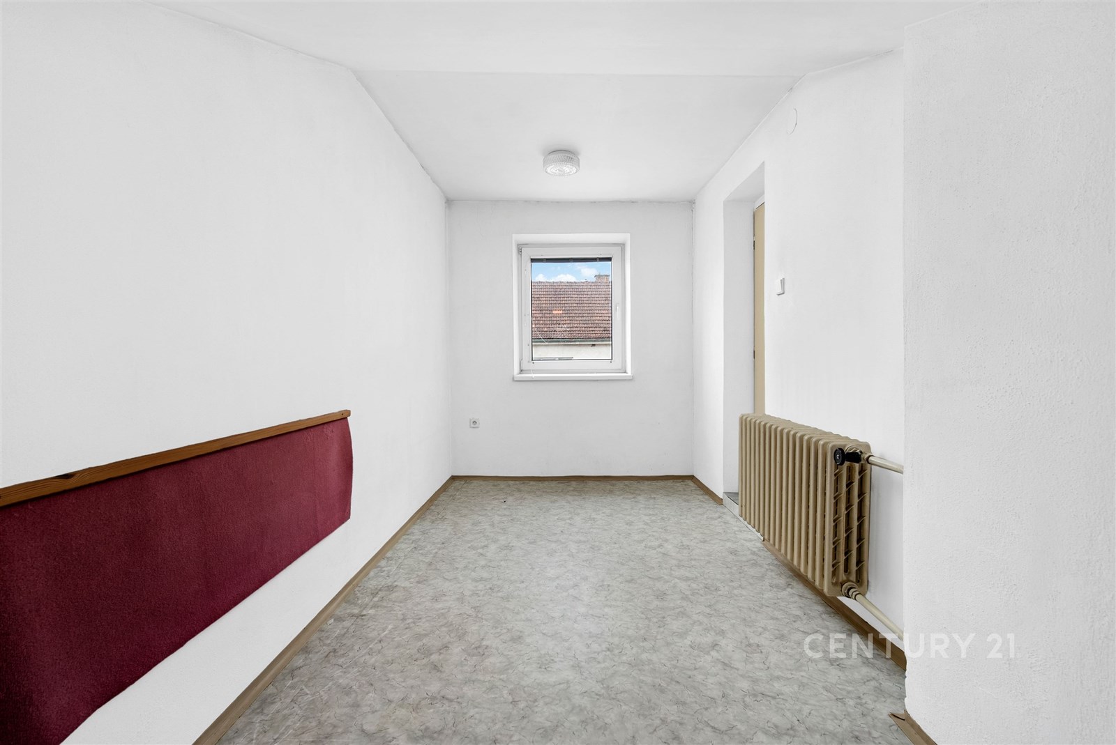 Chodba s dlažbou, bílými stěnami a oknem, obsahuje