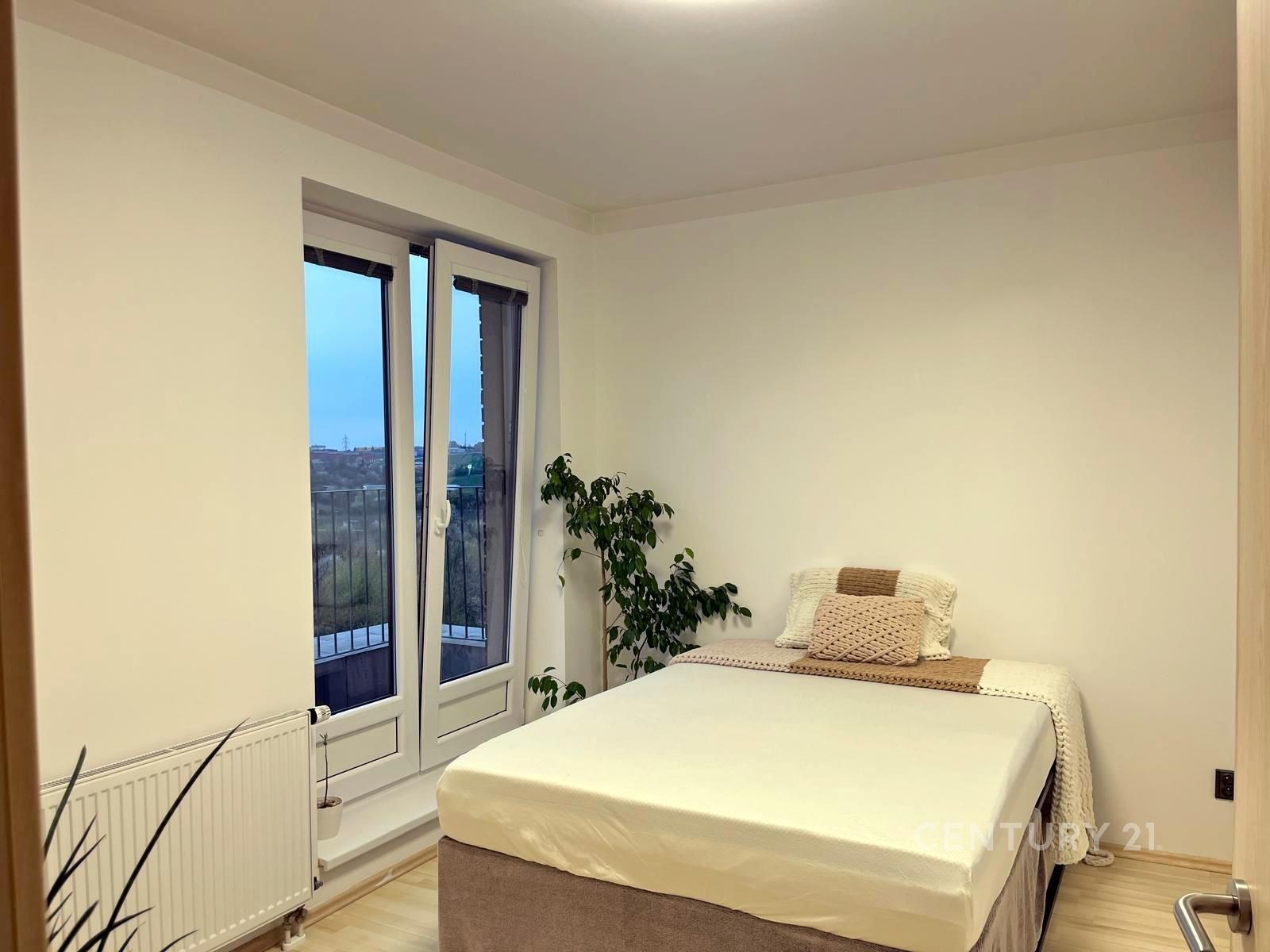 Světlá ložnice s velkými okny, které vedou na balk