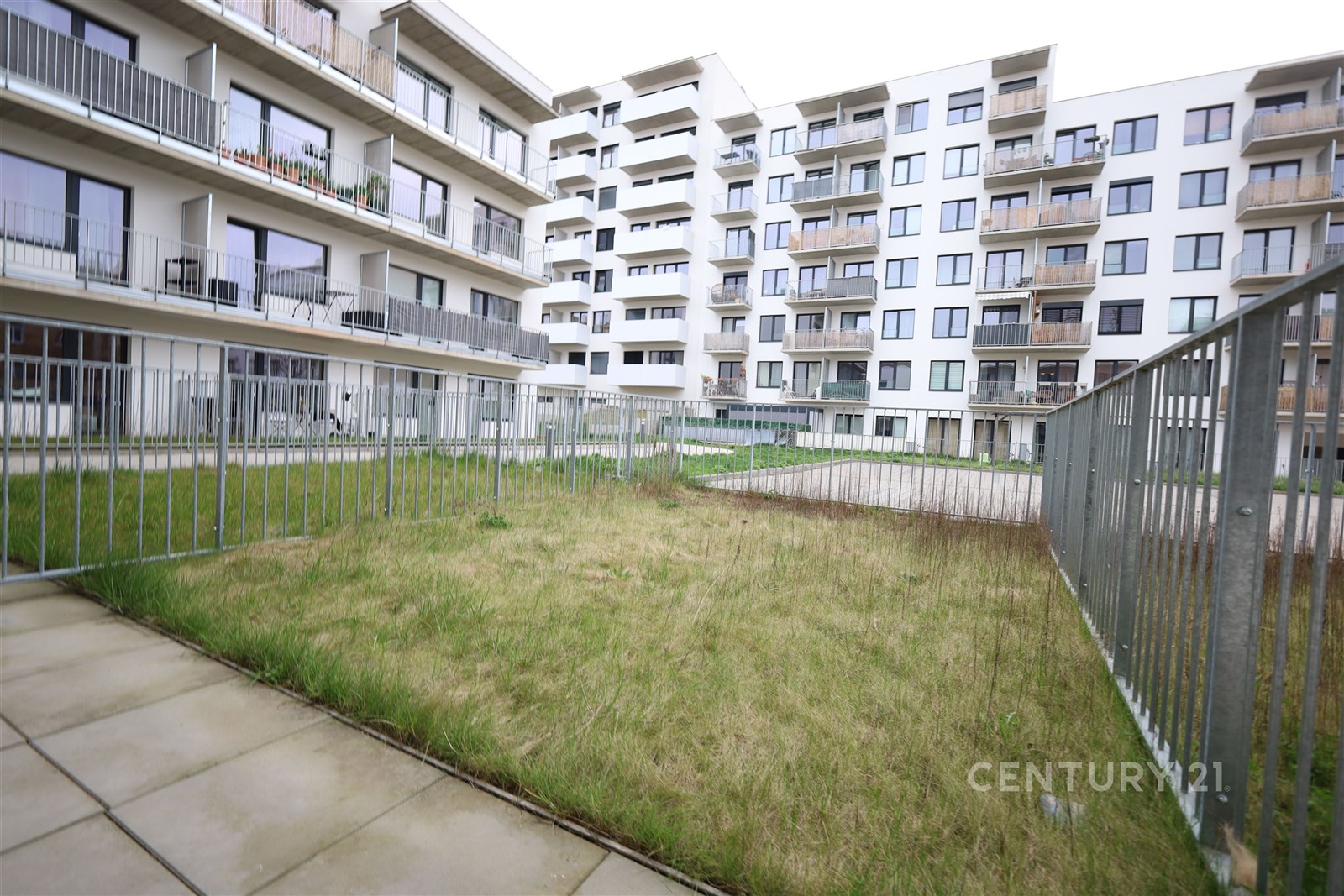 Uzavřený dvůr s trávníkem a dlažbou, obklopený mod