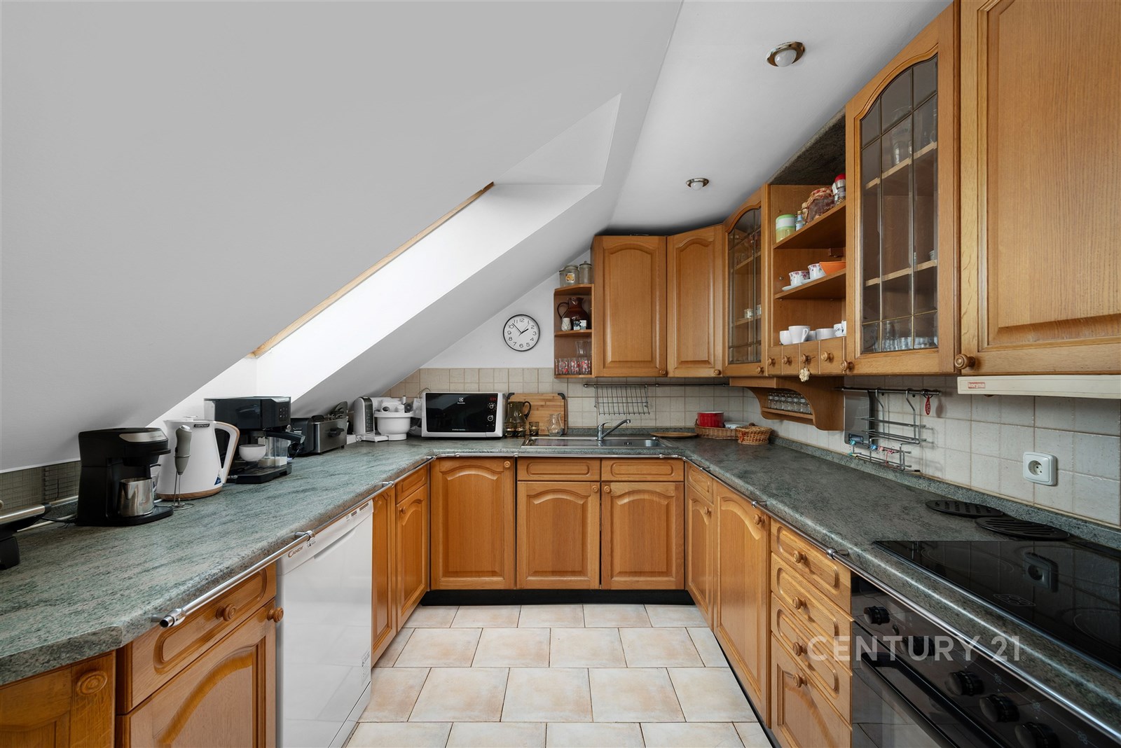 Podkrovní kuchyň s dřevěnými skříňkami, dlažbou a 