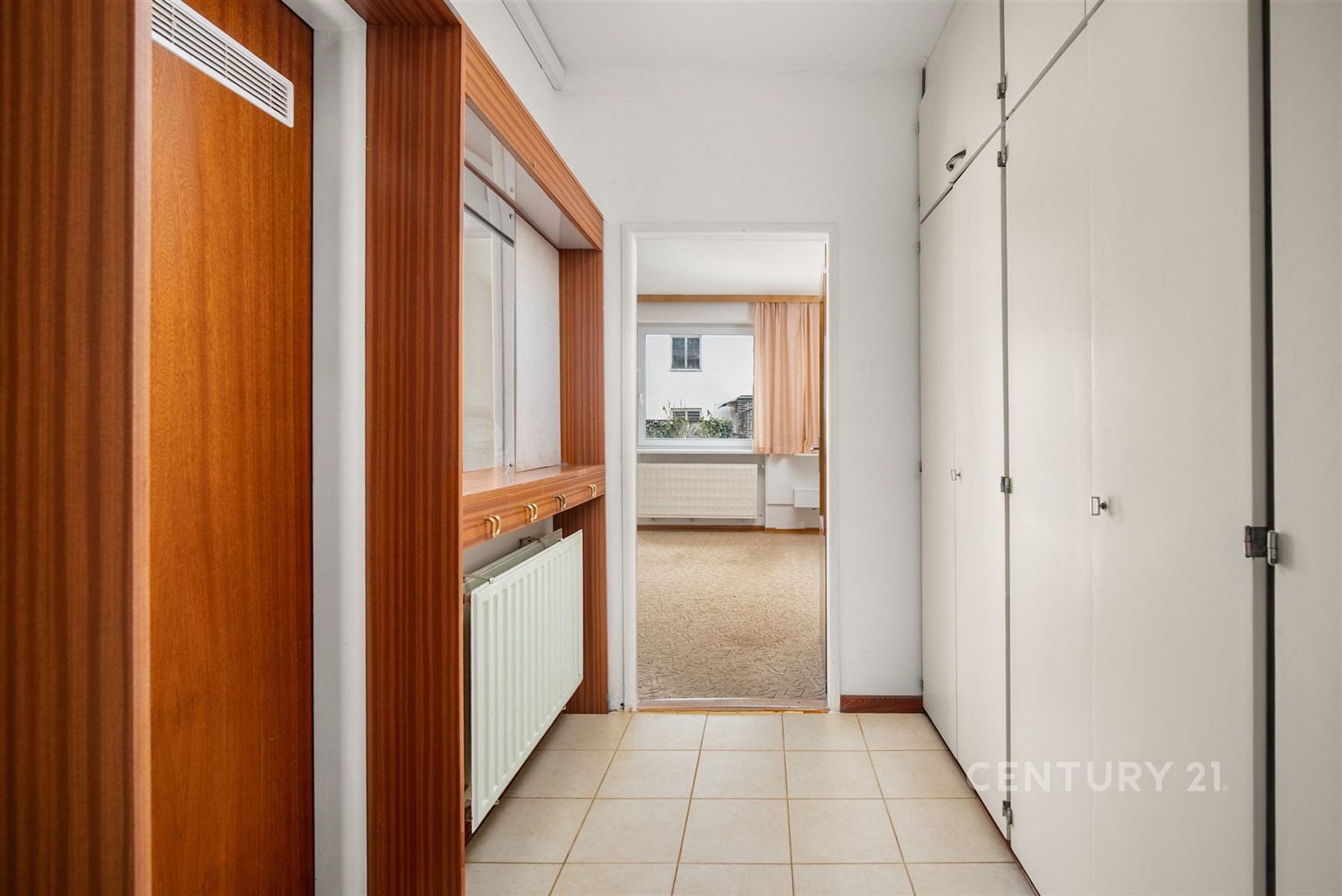 Vstupní chodba se světlou dlažbou a vestavěnými sk