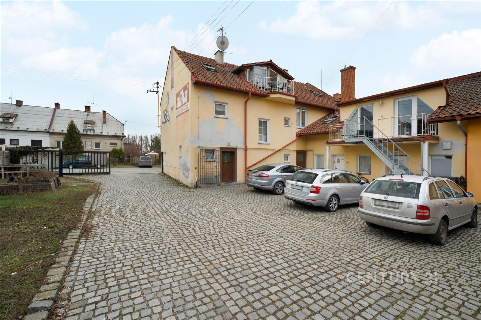 Malý dvůr s dlažbou a parkovacími místy před dvoup