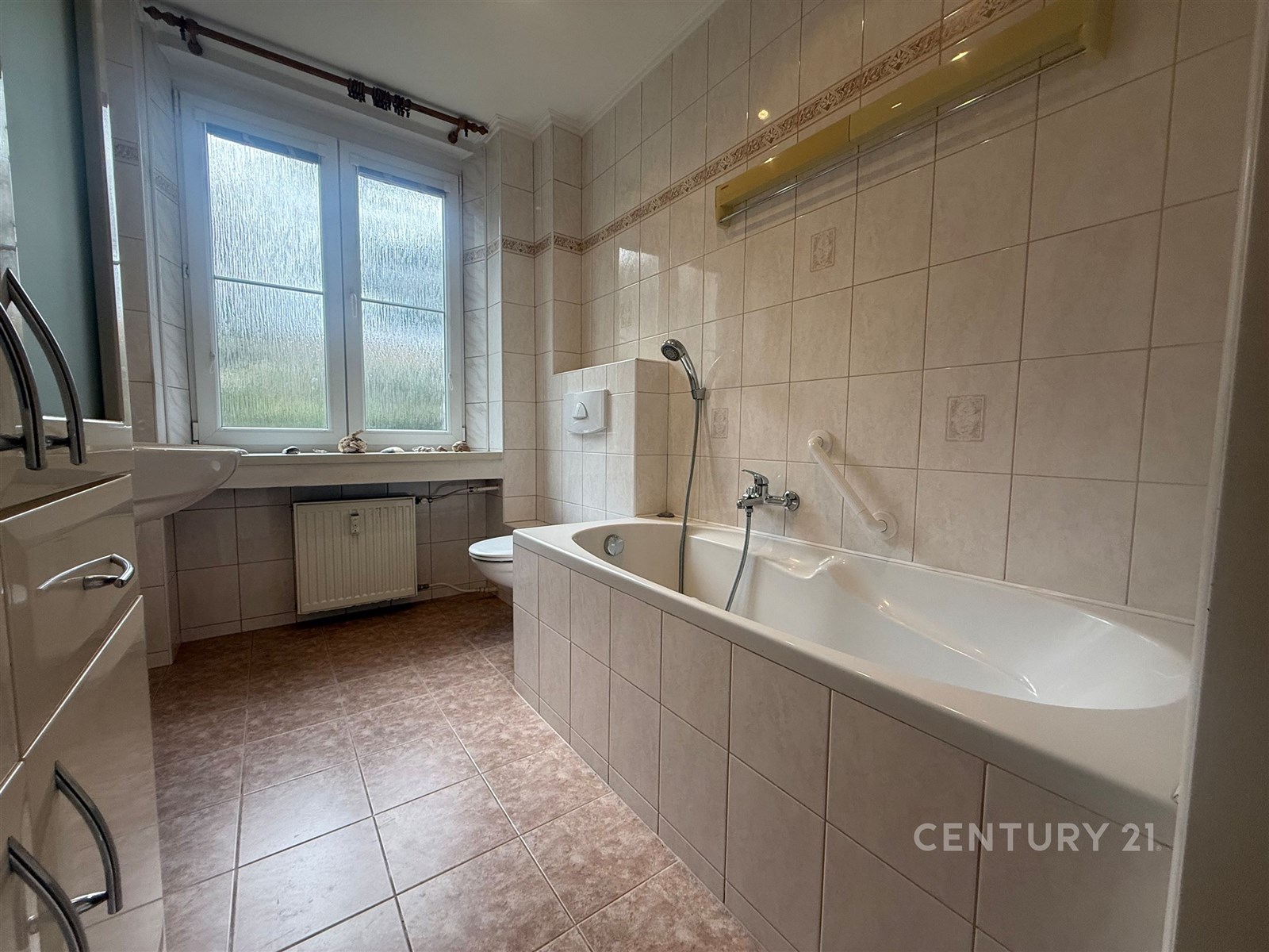 Koupelna s dlažbou a velkou vanou, vybavená umyvad