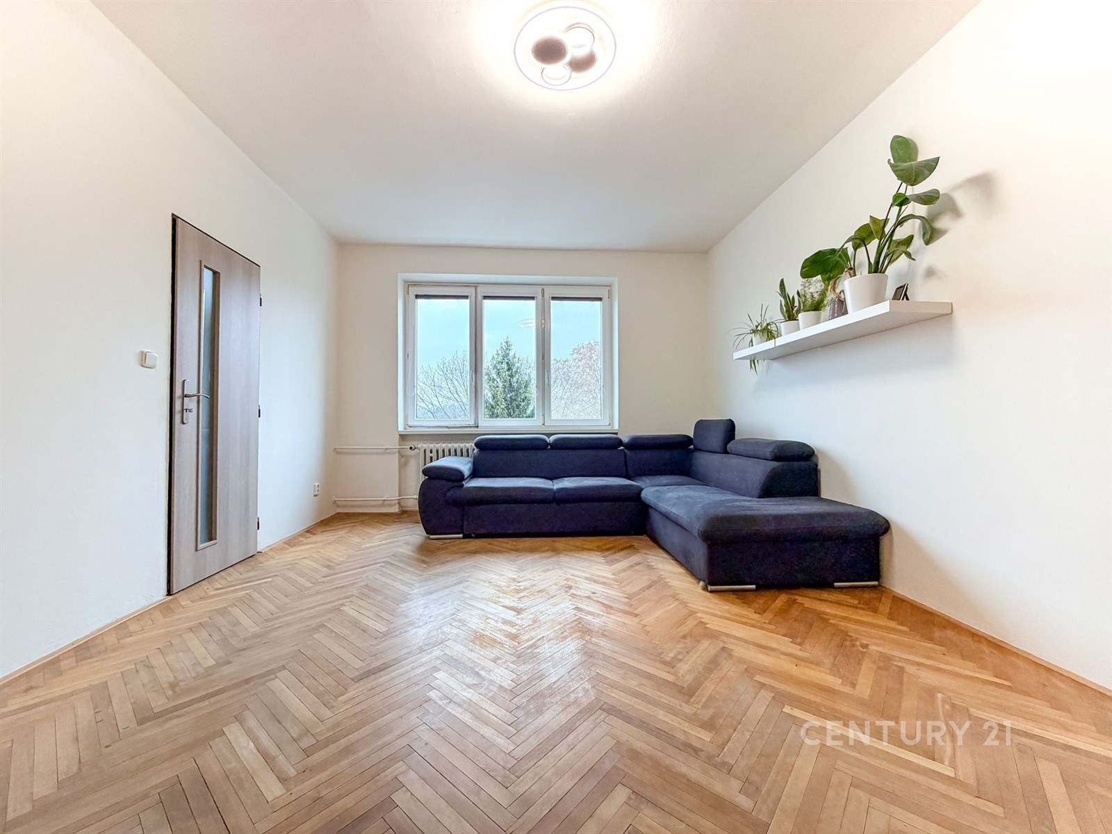 Světlý obývací pokoj s parketovou podlahou a velký
