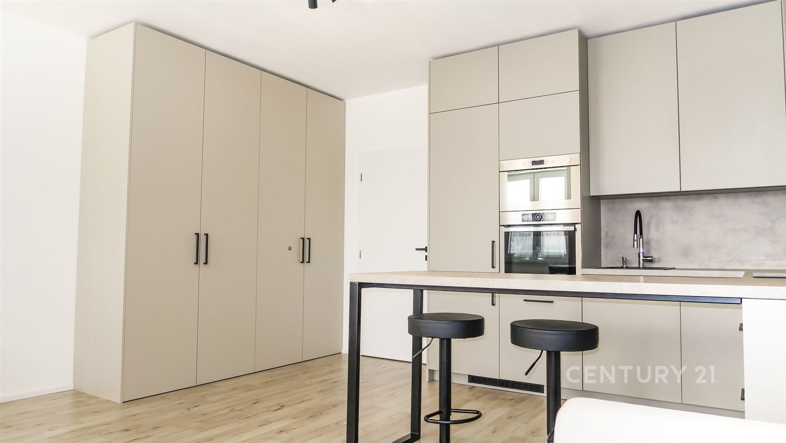 Moderní kuchyň s vestavěnými skříněmi, světlou parketovou podlahou a moderními spotřebiči.