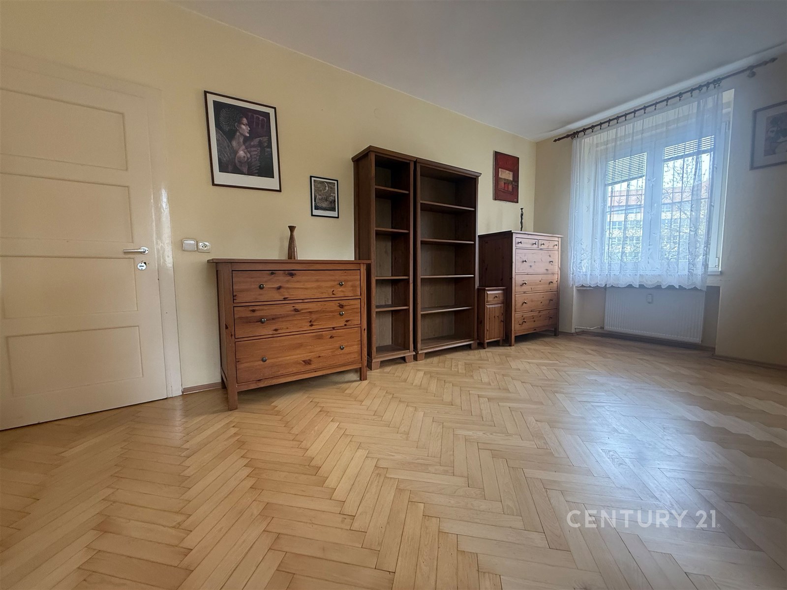 Prázdný pokoj s parketovou podlahou, velkými okny 