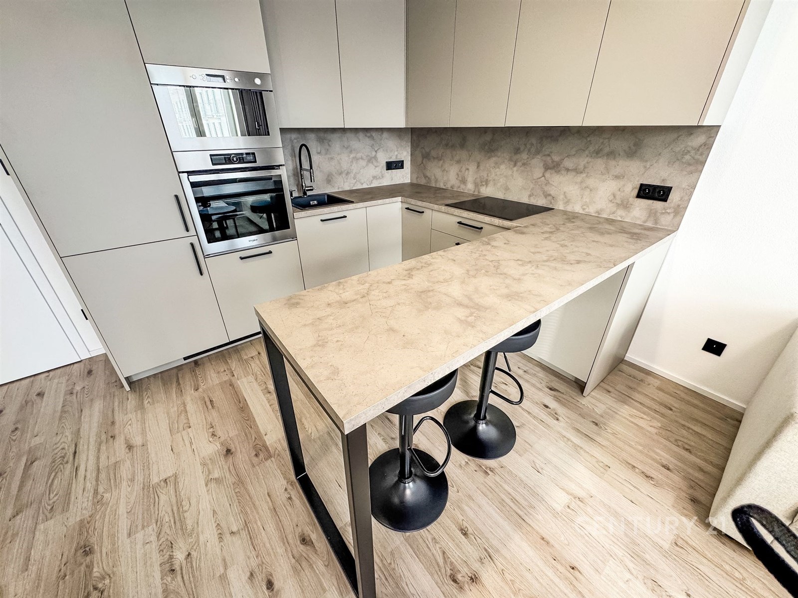 Moderní kuchyň s parketovou podlahou, stylovou pracovní deskou z kamene a vestavěnými spotřebiči, ideální pro moderní bydlení.