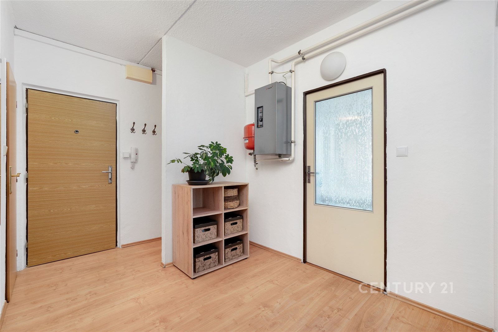 Vstupní hala s parketovou podlahou, moderními vestavěnými policemi a dřevěnými dveřmi nabízí přístup do dalších částí bytu.