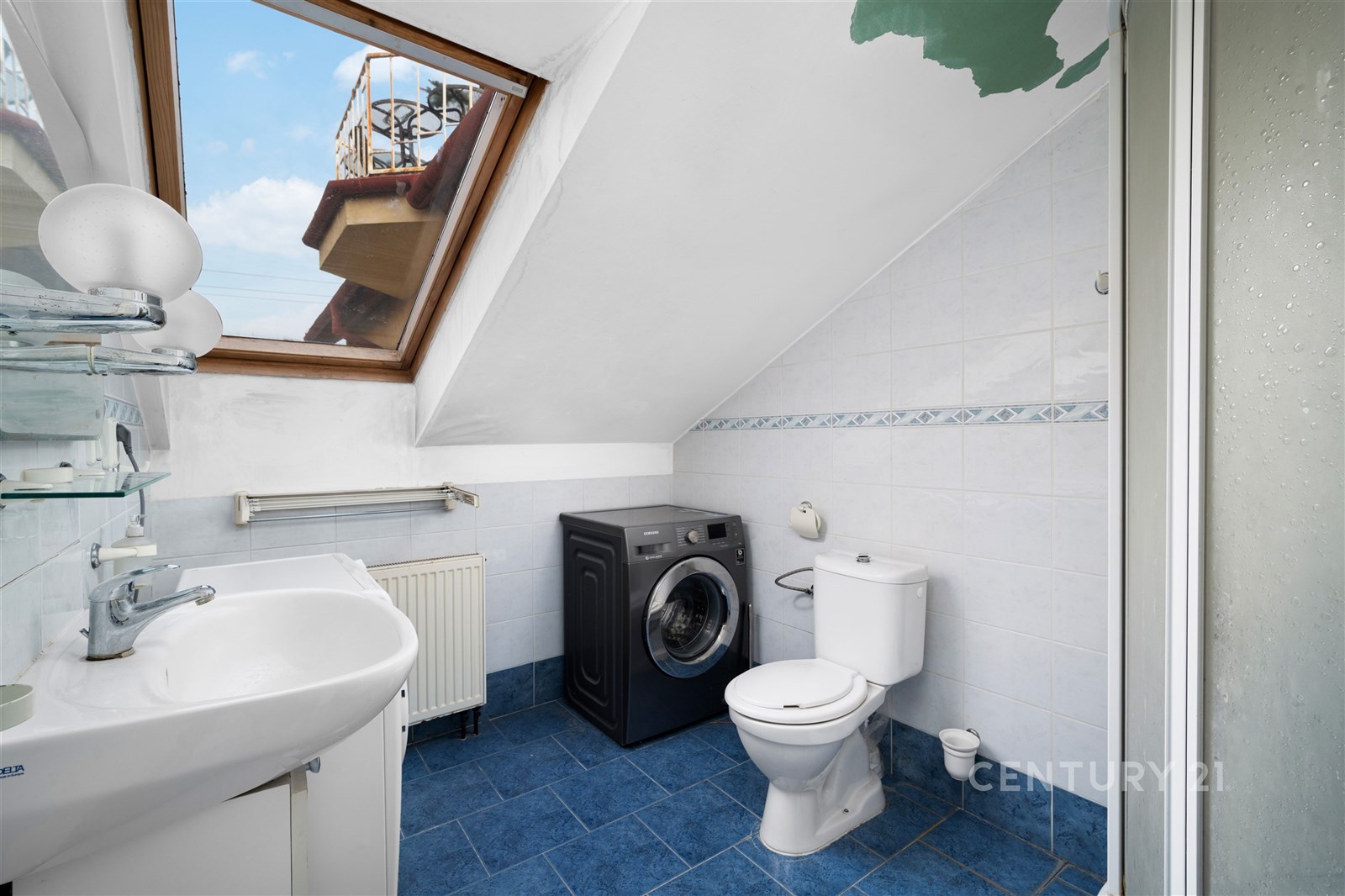 Podkrovní koupelna s modrou dlažbou, střešním okne