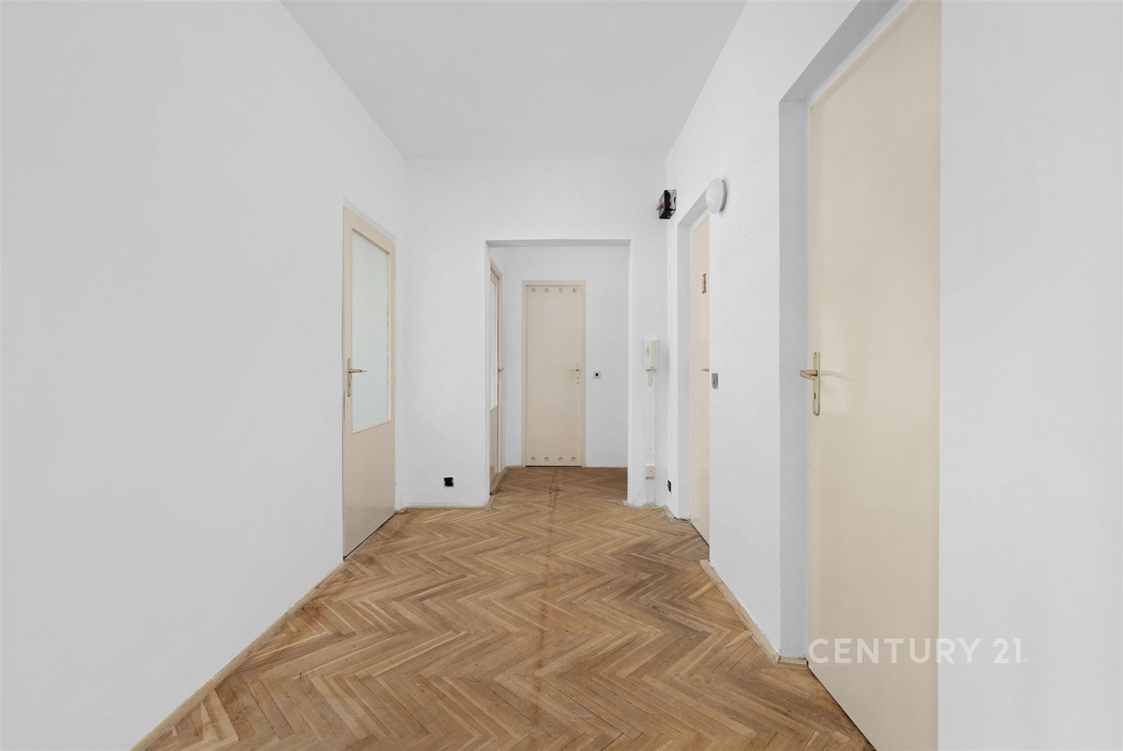 Prostorná chodba s parketovou podlahou, světlé stěny a několik dveří, moderní styl