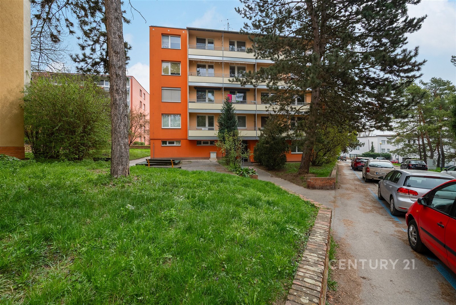 Čtyřpodlažní bytový dům s oranžovou fasádou a balk