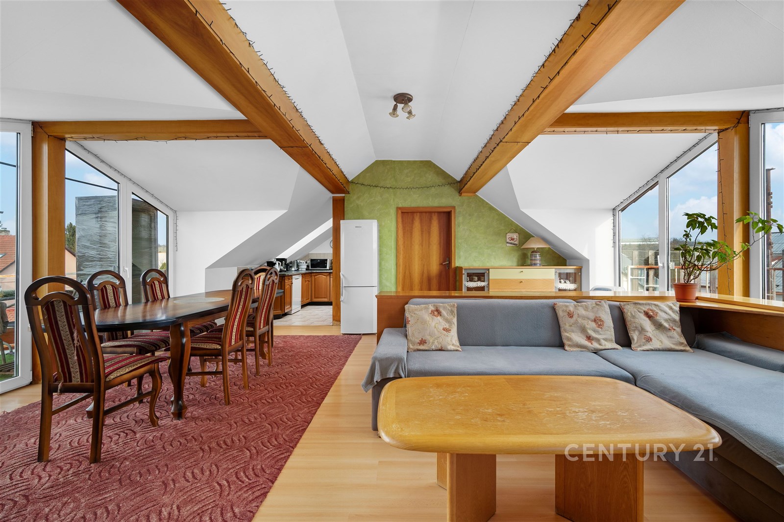 Podkrovní obývací pokoj s dřevěnými trámy, velkými