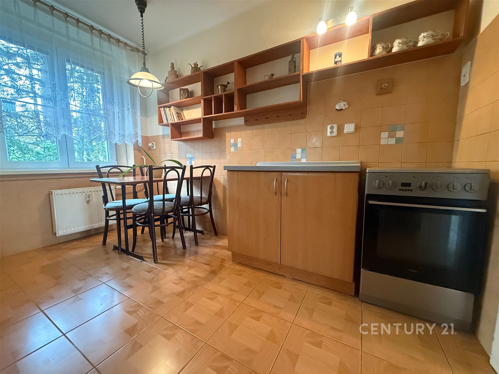 Kuchyň s dlažbou, dřevěnými skříňkami a velkými ok