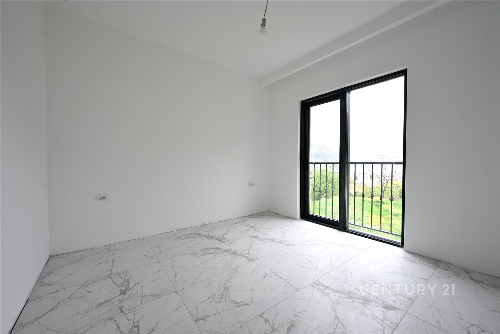 Světlá ložnice s dlažbou a velkým oknem, které poskytuje výhled do zahrady, moderní minimalistický design bez nábytku.