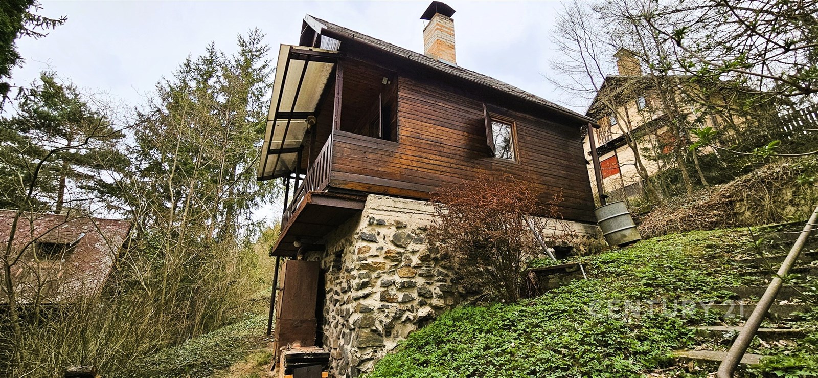 Horská chata s dřevěnou fasádou a kamenným základem, obklopená přírodou. Rustikální styl, útulné útočiště v přírodě.