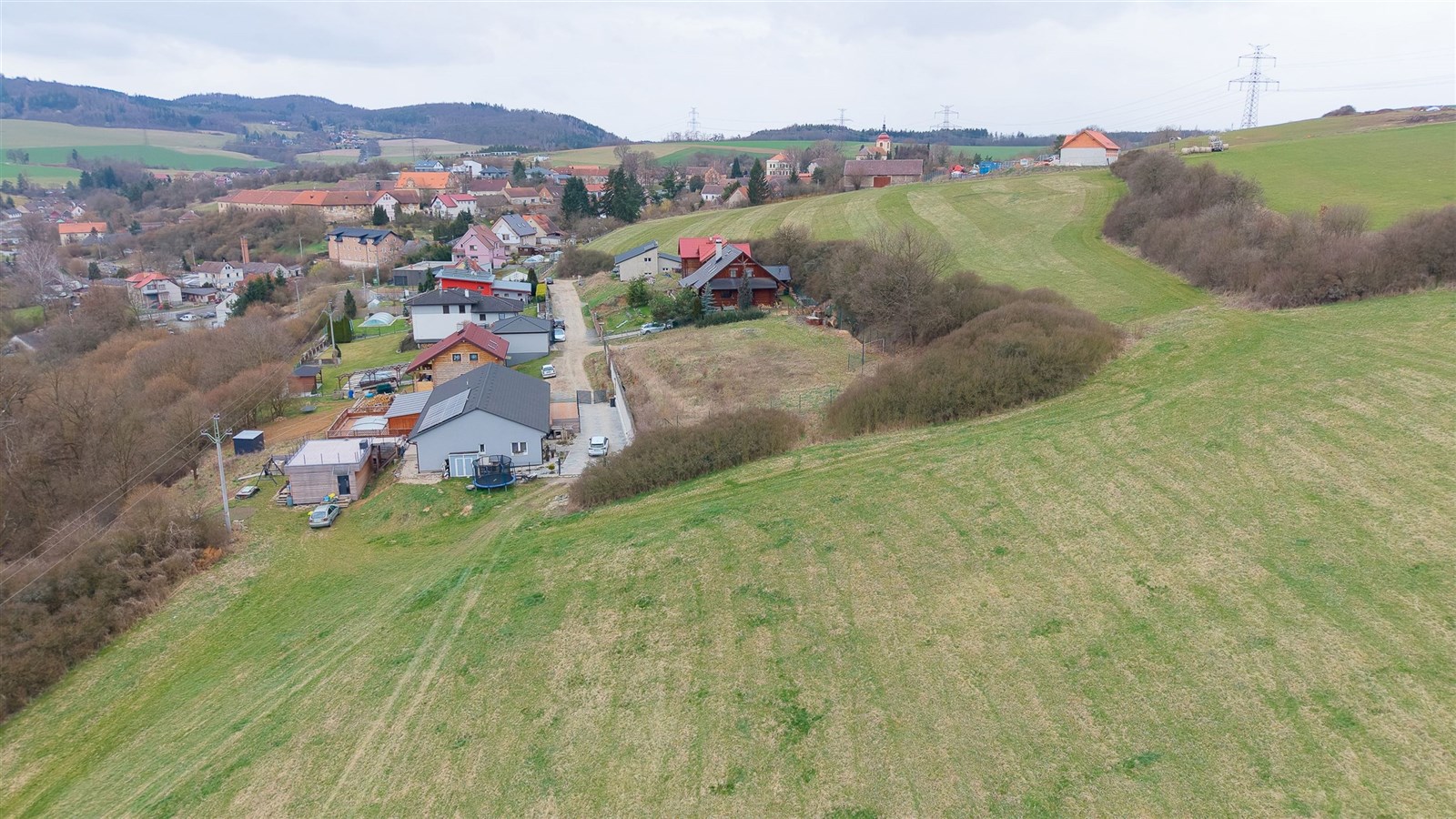 Prázdný stavební pozemek na okraji obce, obklopený