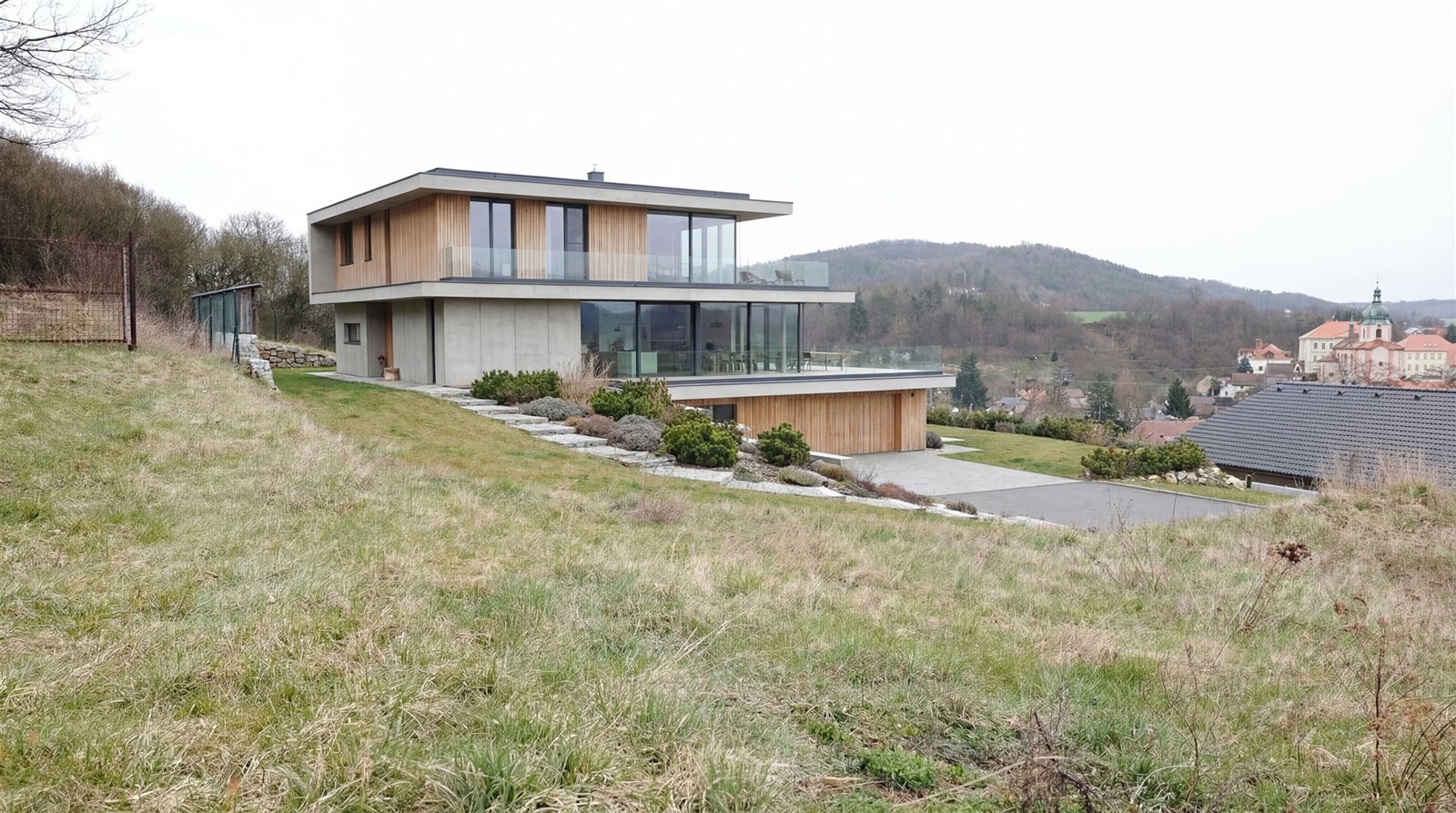 Moderní vila s dřevěným obkladem a velkými okny na