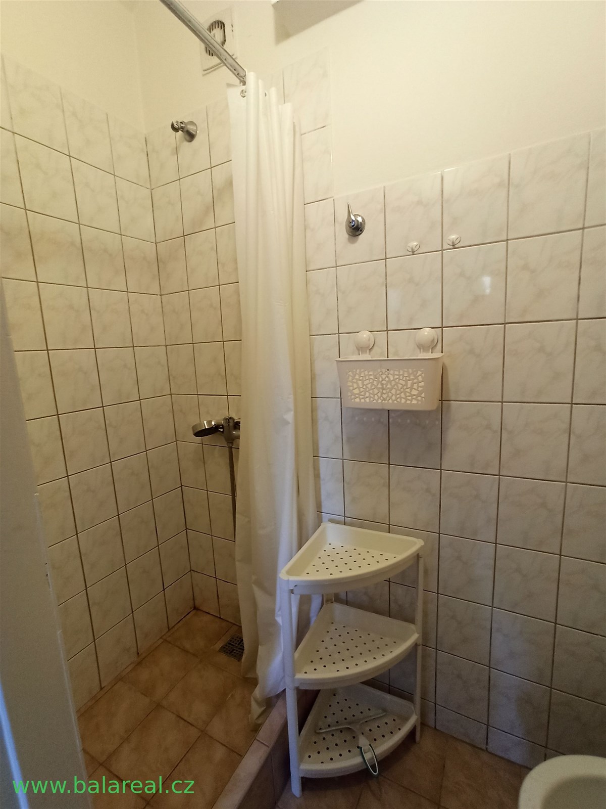 Koupelna s dlažbou a sprchovým koutem, vybavena je