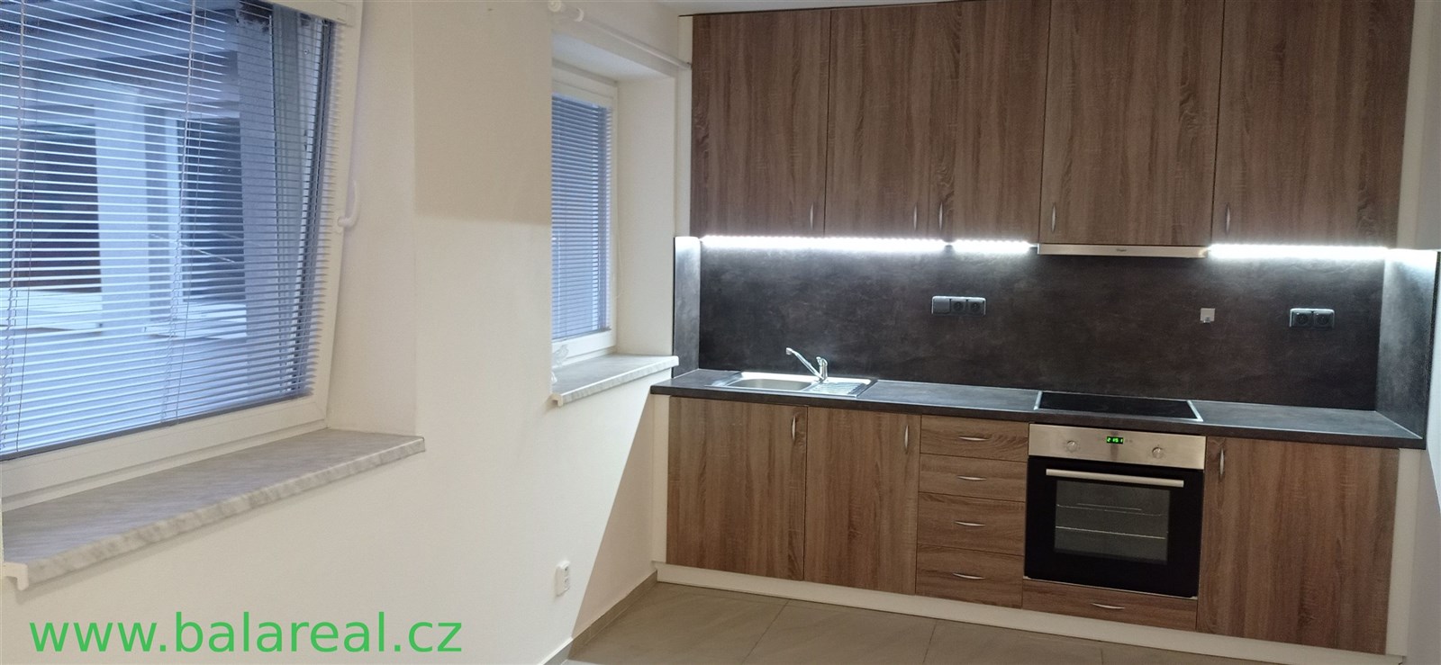 Moderní kuchyň se dřevěnými skříňkami, dlažbou a v