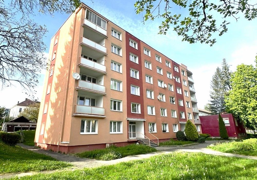 Čtyřpodlažní bytový dům s balkony, obklopený trávníkem a zelení, v dobrém stavu, nachází se v klidné lokalitě.