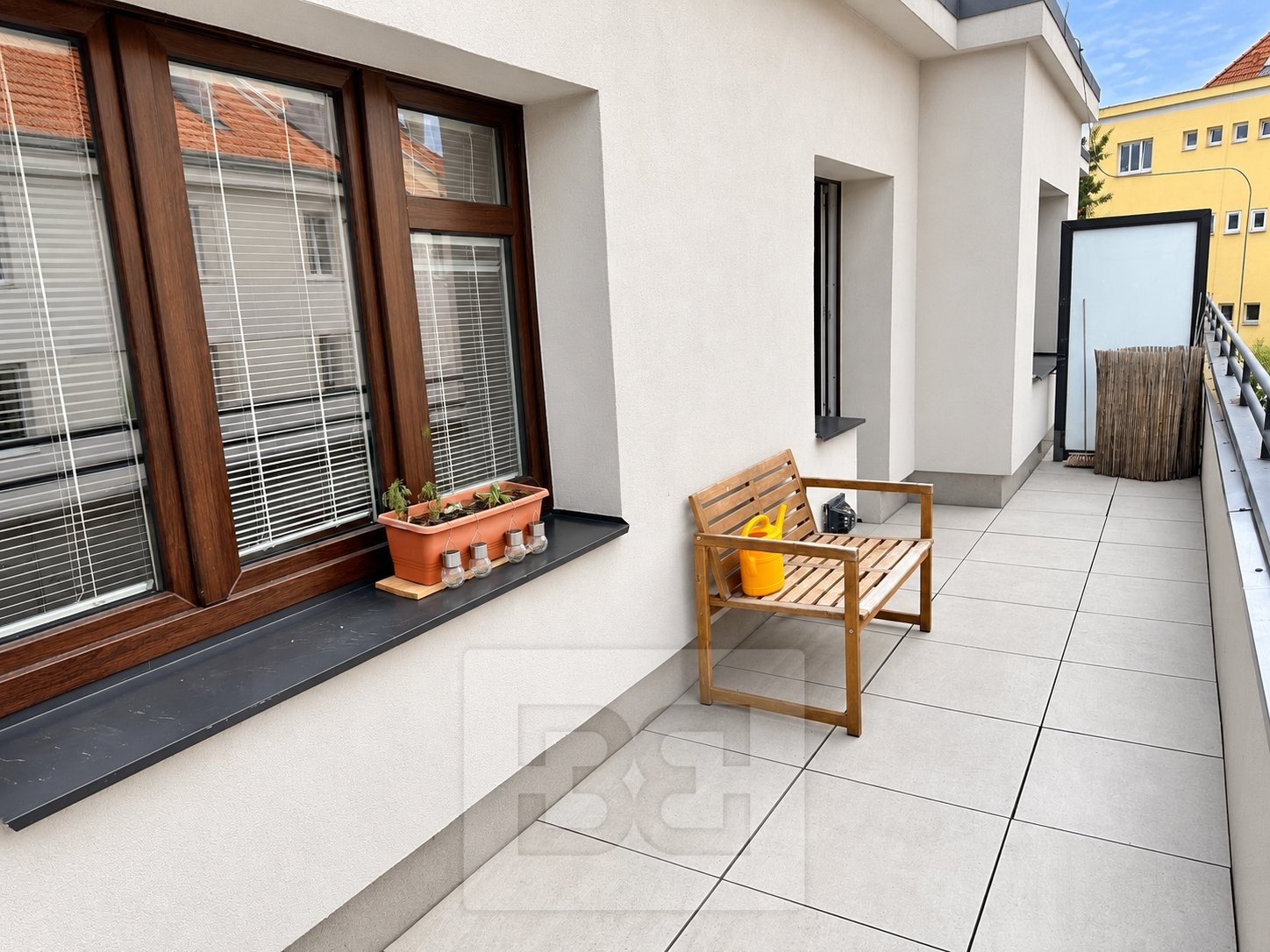 Moderní balkon s dřevěnou lavicí a květináčem