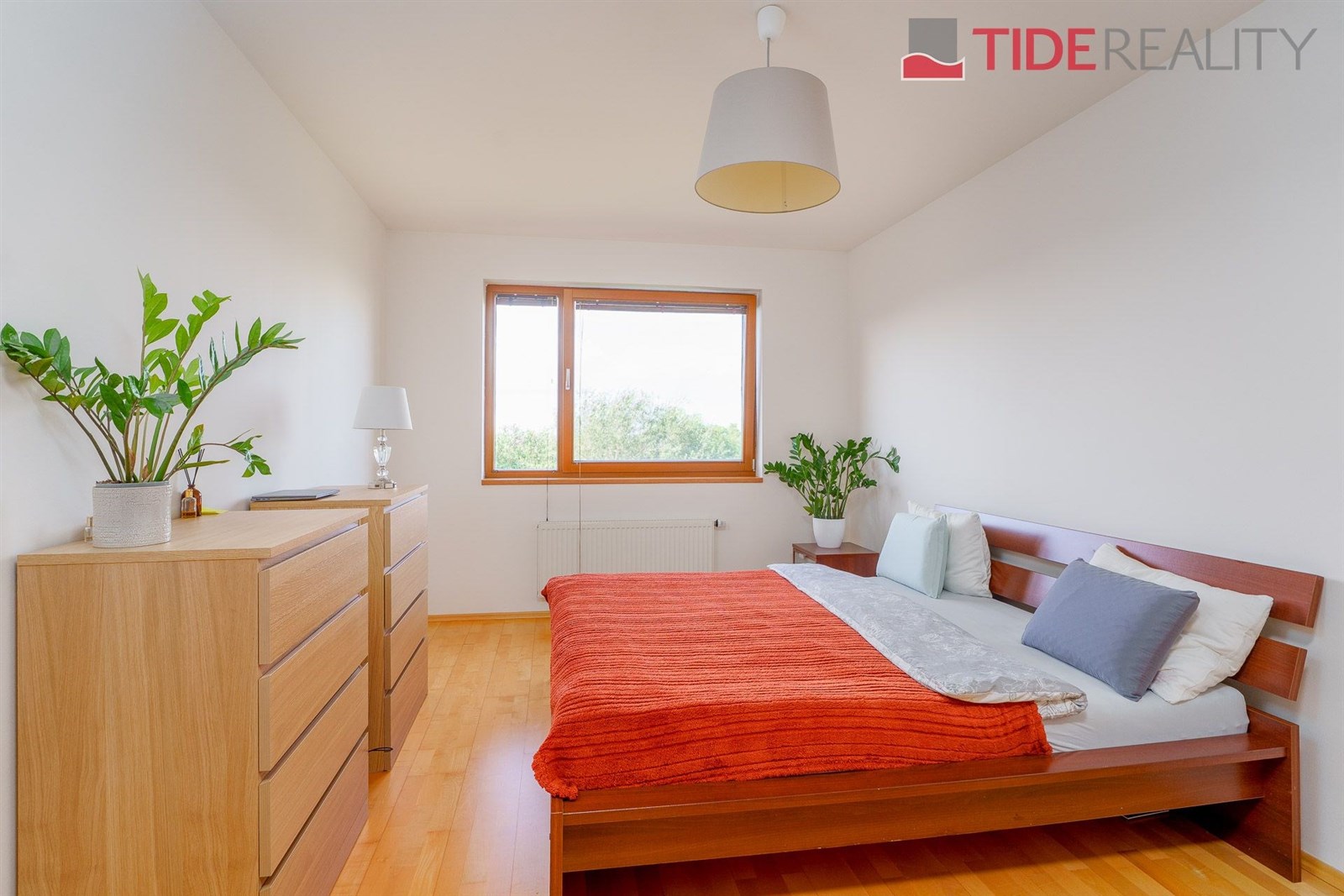 Prostorná ložnice s parketovou podlahou, dřevěným nábytkem a velkými okny, které zajišťují světlé a vzdušné prostředí.