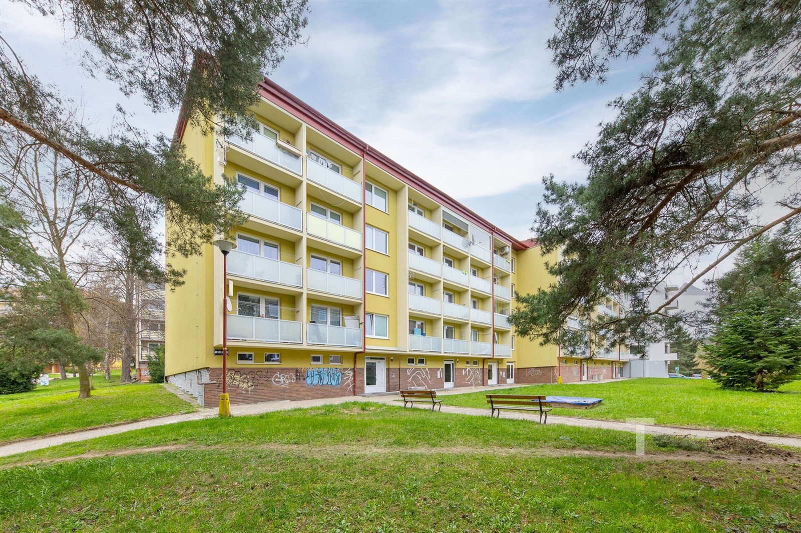 Čtyřpatrový panelový bytový dům s balkony, obklope