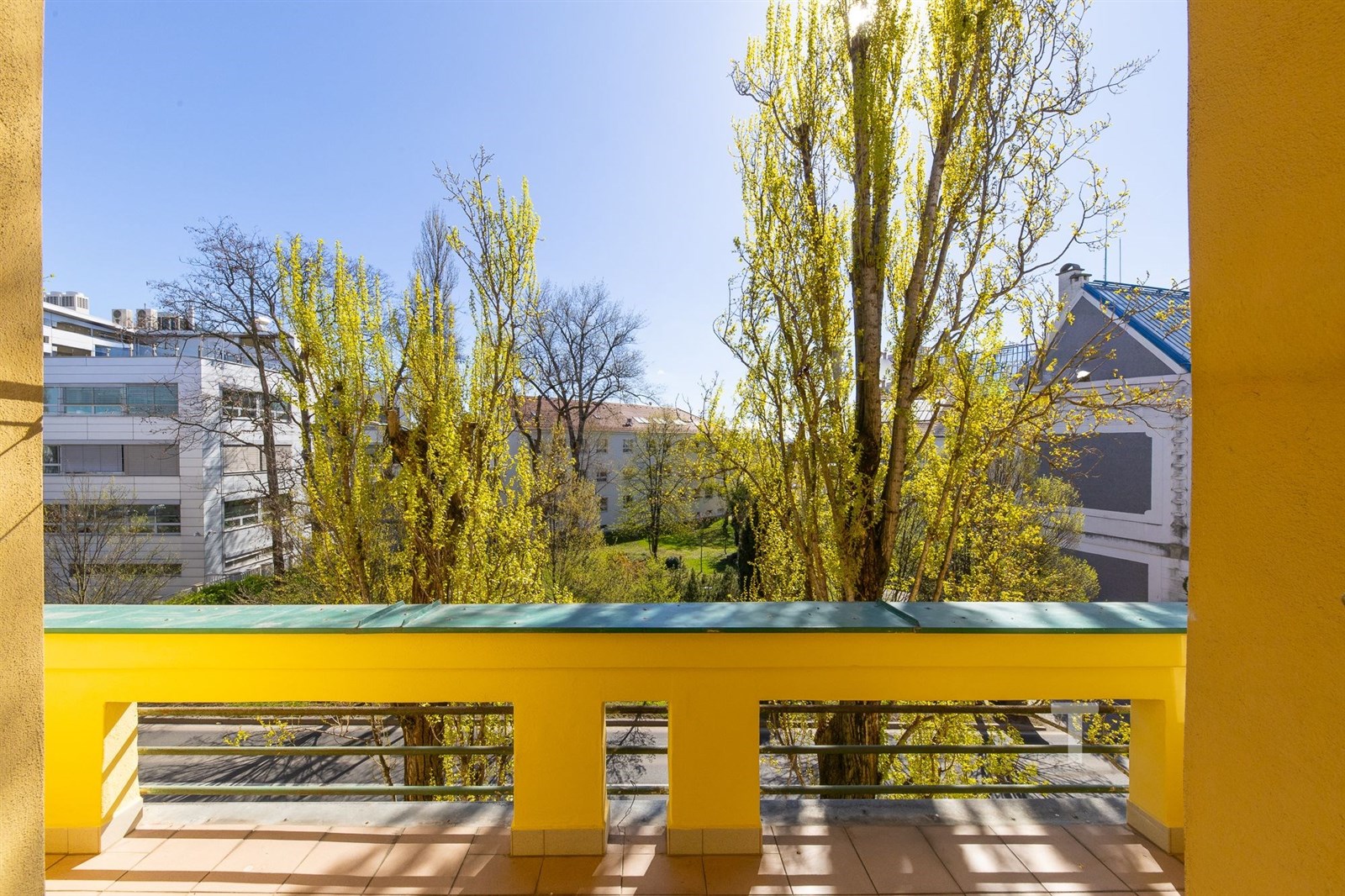 Výhled z balkonu s dlažbou, obklopený zelení a str