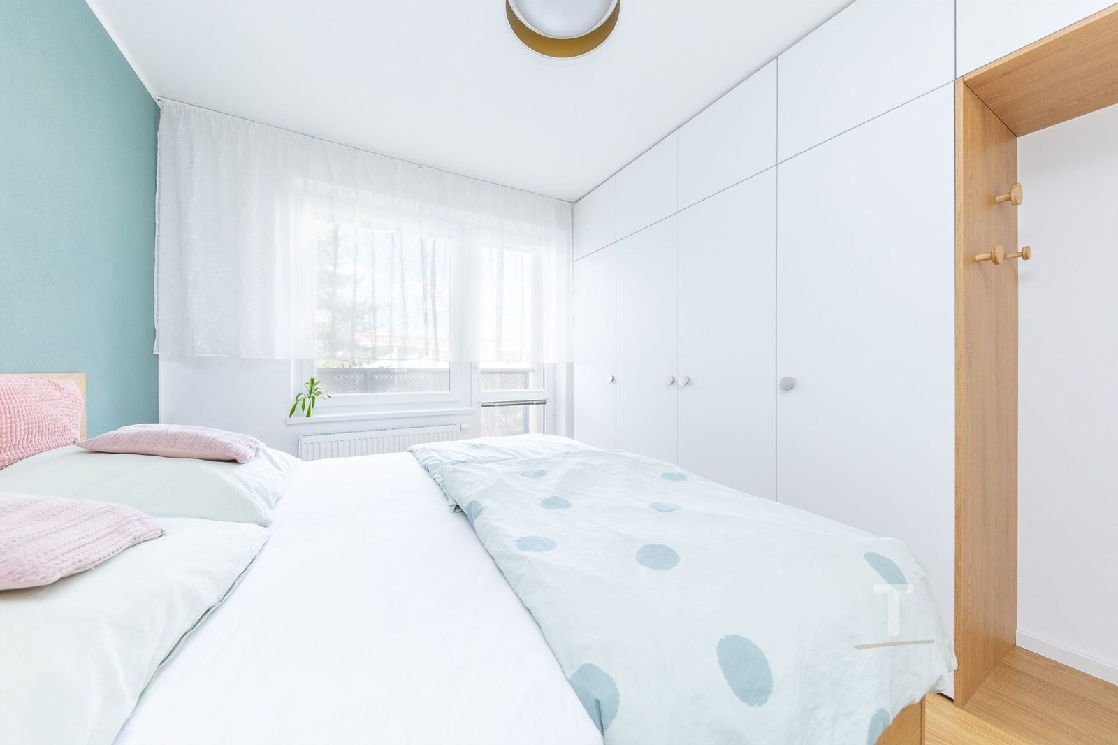 Světlá ložnice se vestavěnými skříněmi, parketovou