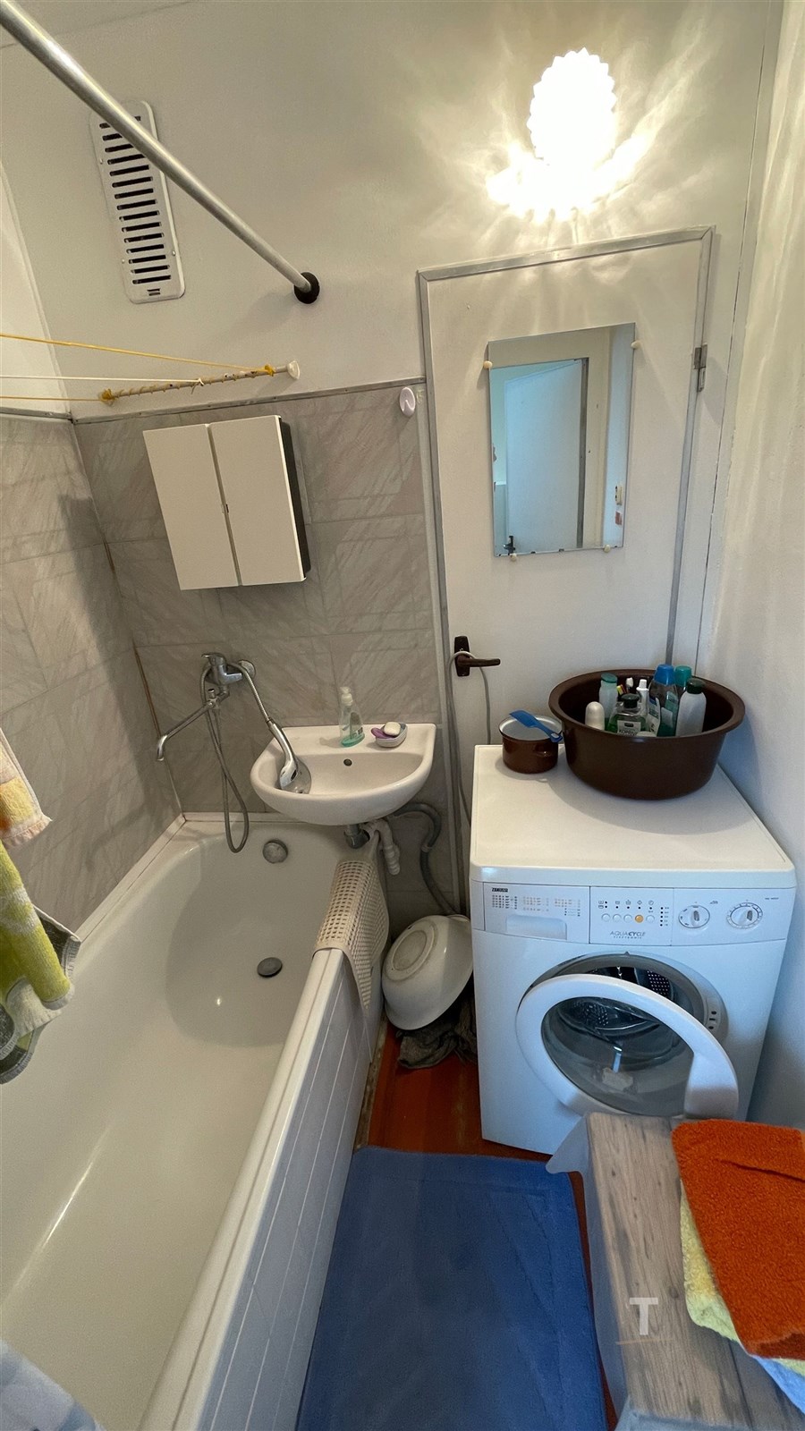 Malá koupelna s bílou vanou, moderními dlaždicemi 