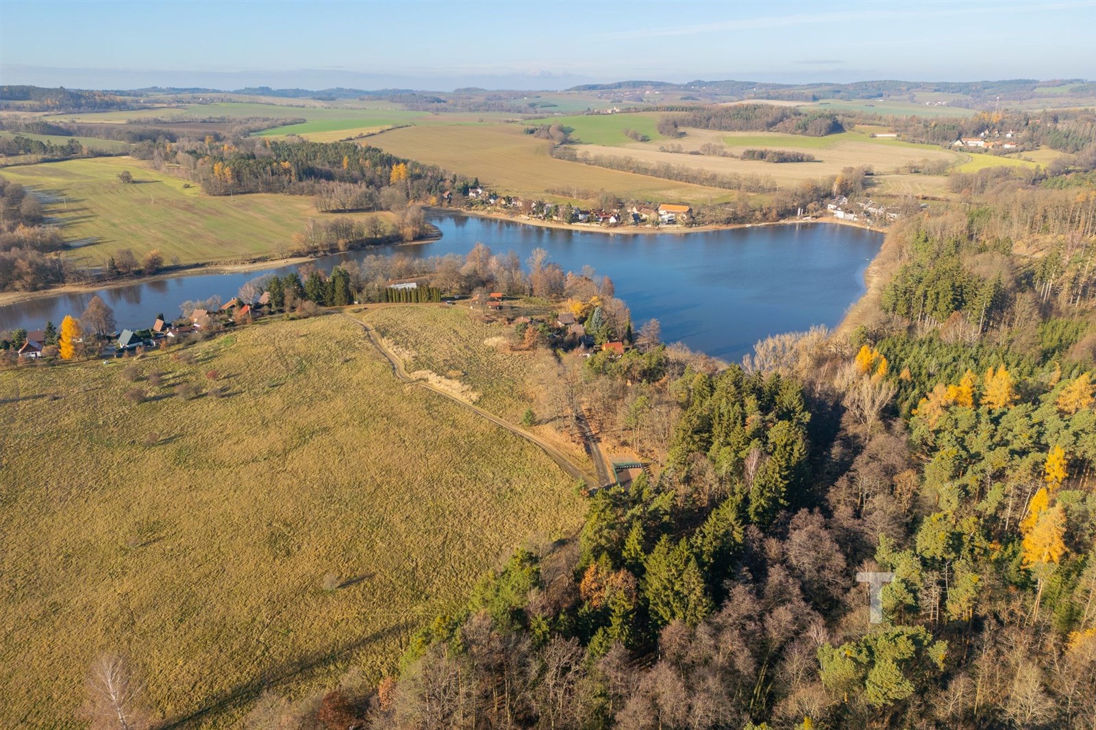 Pozemek u jezera obklopený přírodou s výhledem na lesy a louky, ideální pro rekreaci nebo výstavbu rekreační chaty.