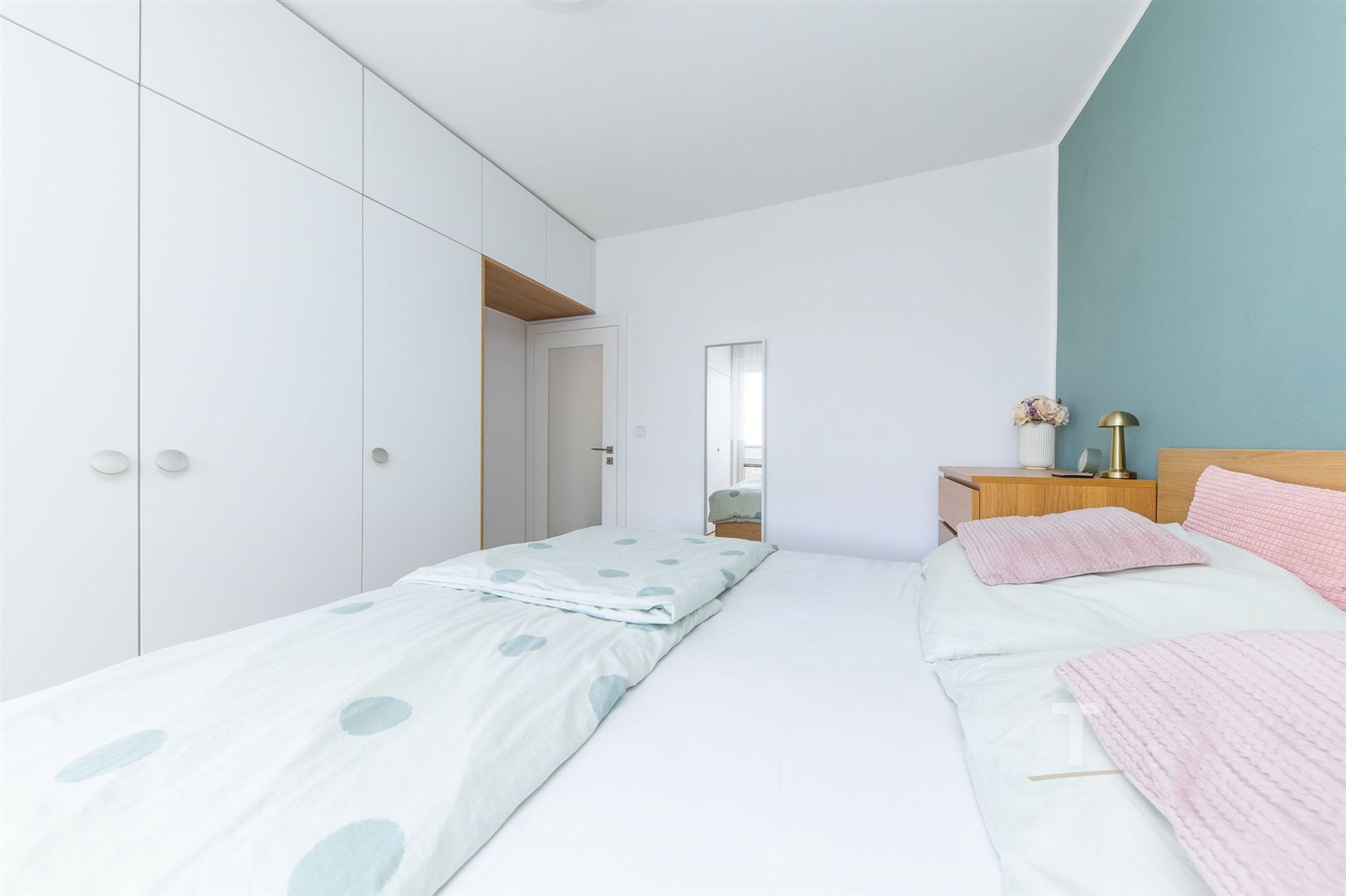 Světlá ložnice s vestavěnými skříněmi a dřevěným n