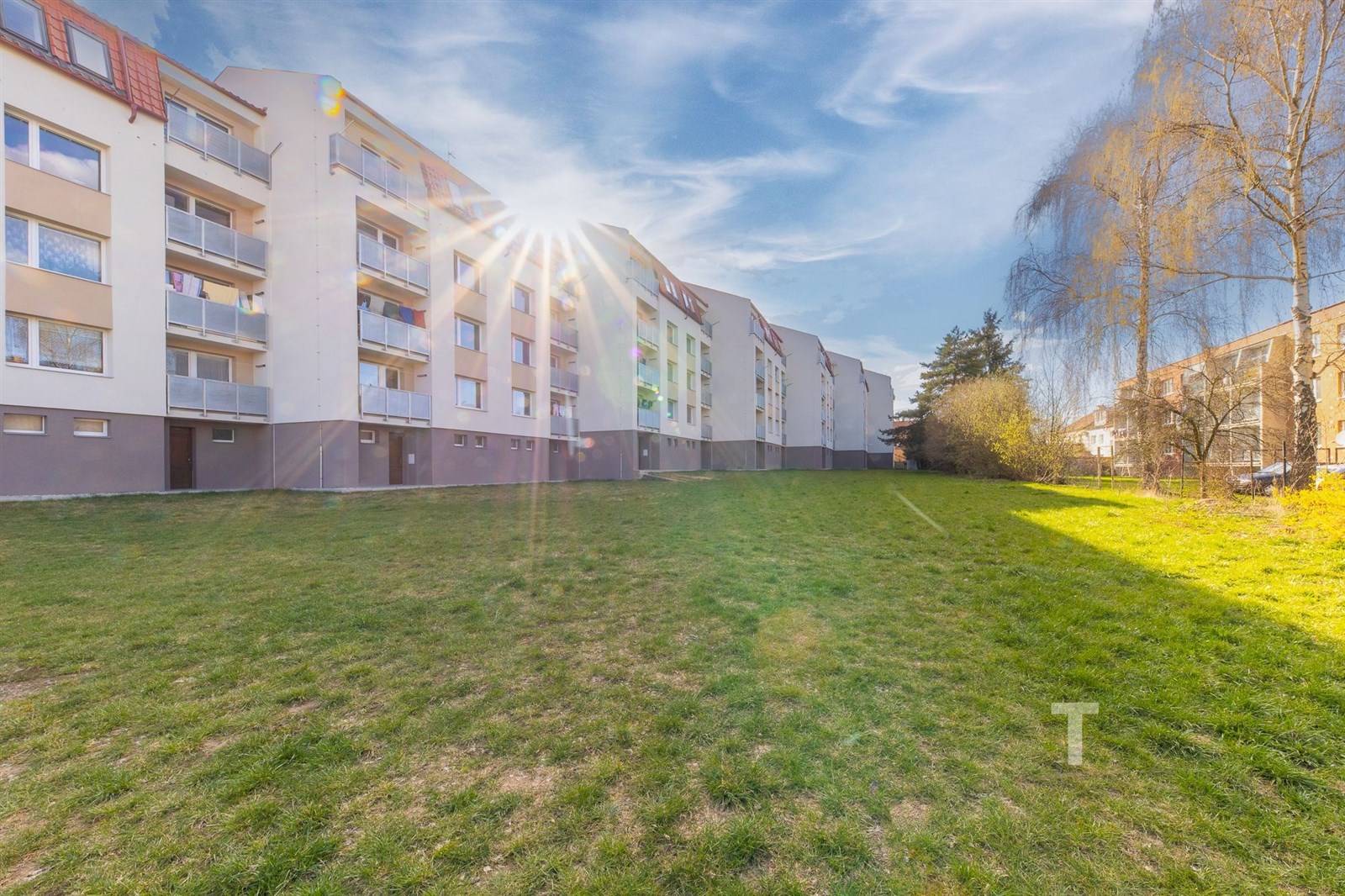 Exteriér bytového domu s udržovaným trávníkem, bal