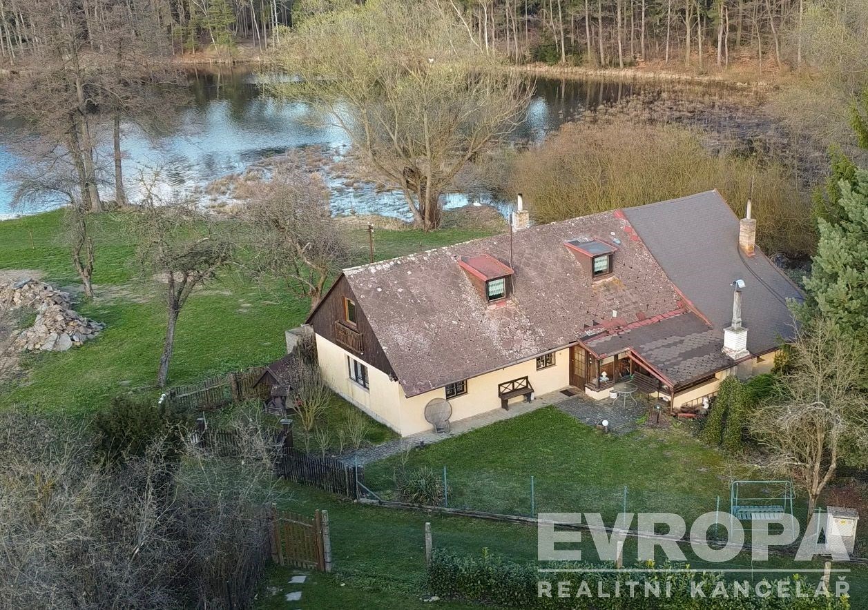 Rustikální venkovský dům u vodní plochy, obklopený