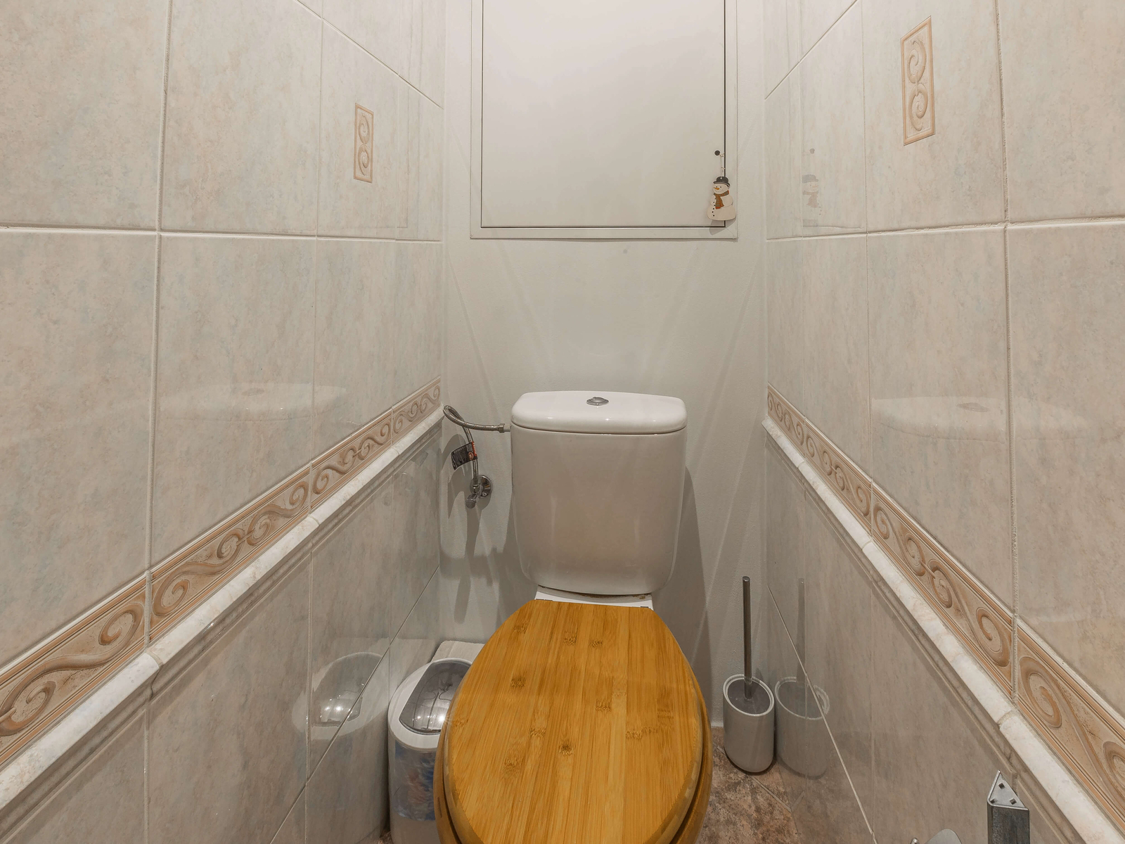 Samostatné WC s dřevěným prkénkem a světlým obklad