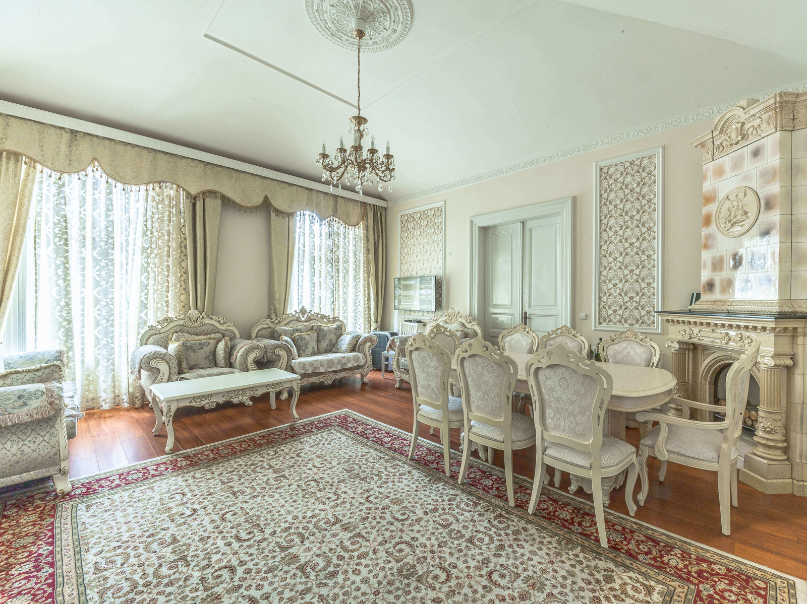 Reprezentativní obývací pokoj bytu 3+1, štuky, krb a vysoké stropy. Elegantní nábytek, světlý prostor.