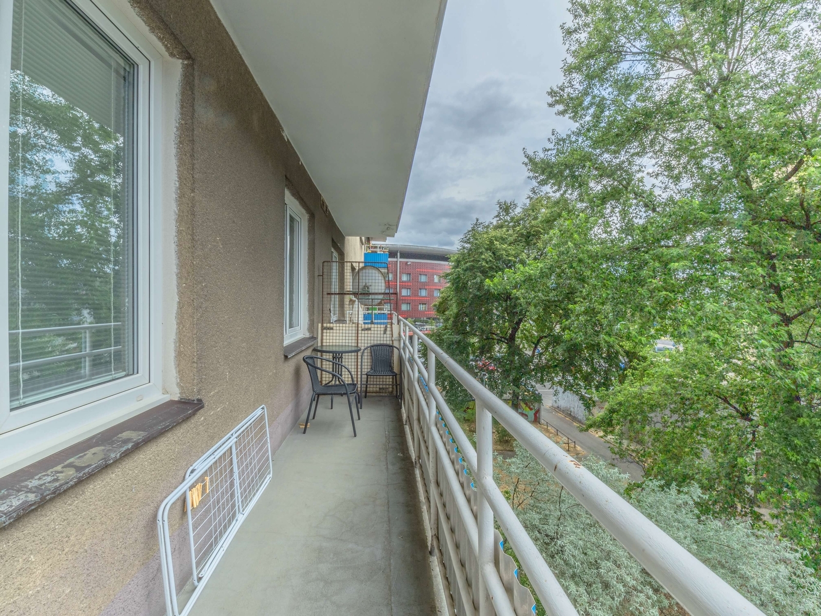 Podlouhlý balkon obklopený korunami stromů; dostat