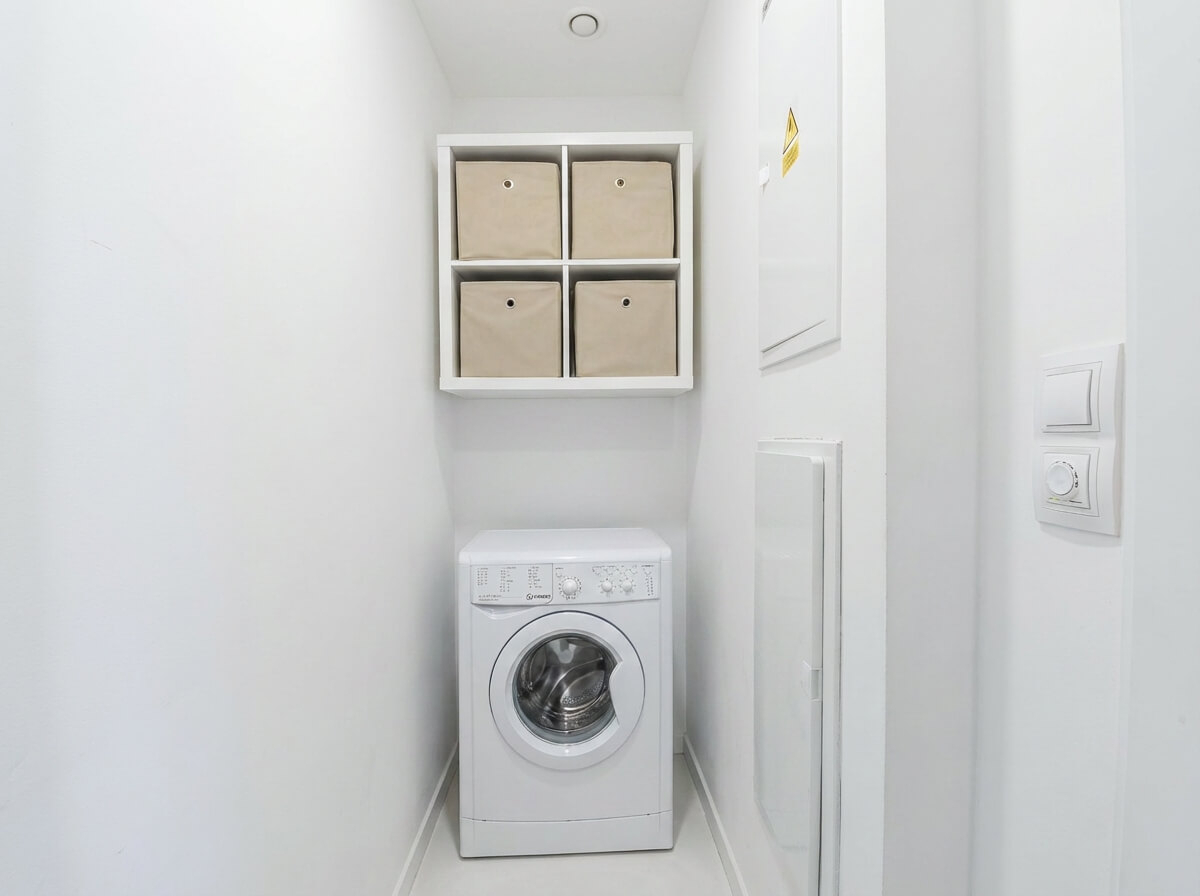 Praktická technická místnost s prostorem pro pračku a úložné řešení.