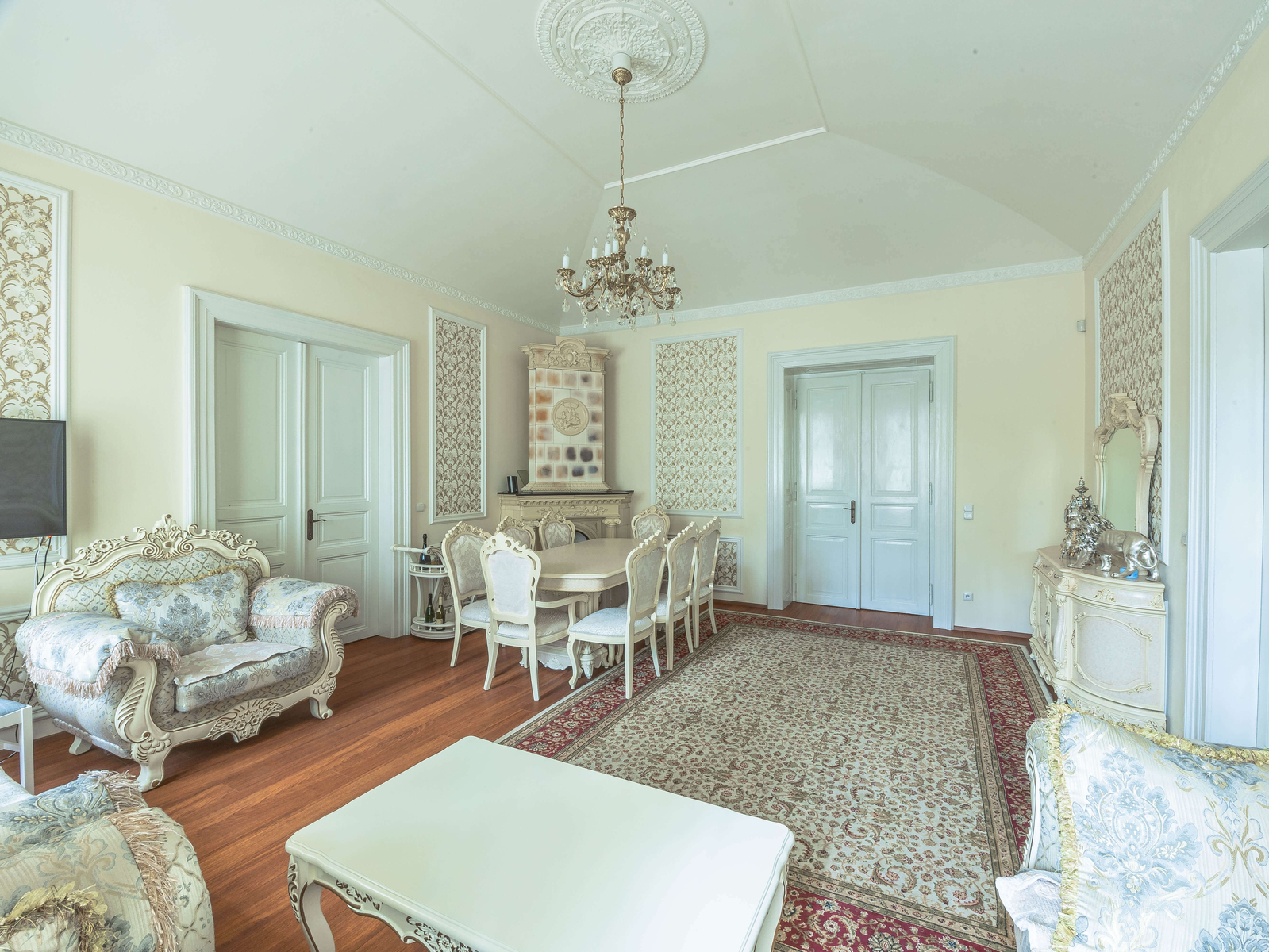 Obývací pokoj bytu 3+1 na Mezibranské 19 – lustry, štuky a klasický interiér s kvalitními podlahami.