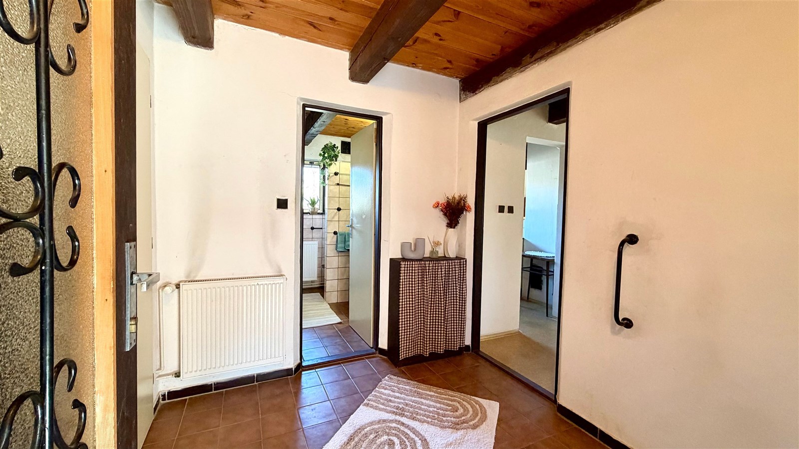 Vstupní hala s dřevěným stropem, dlažbou na podlaze a velkými dveřmi vede do dalších místností, vytváří příjemnou atmosféru.