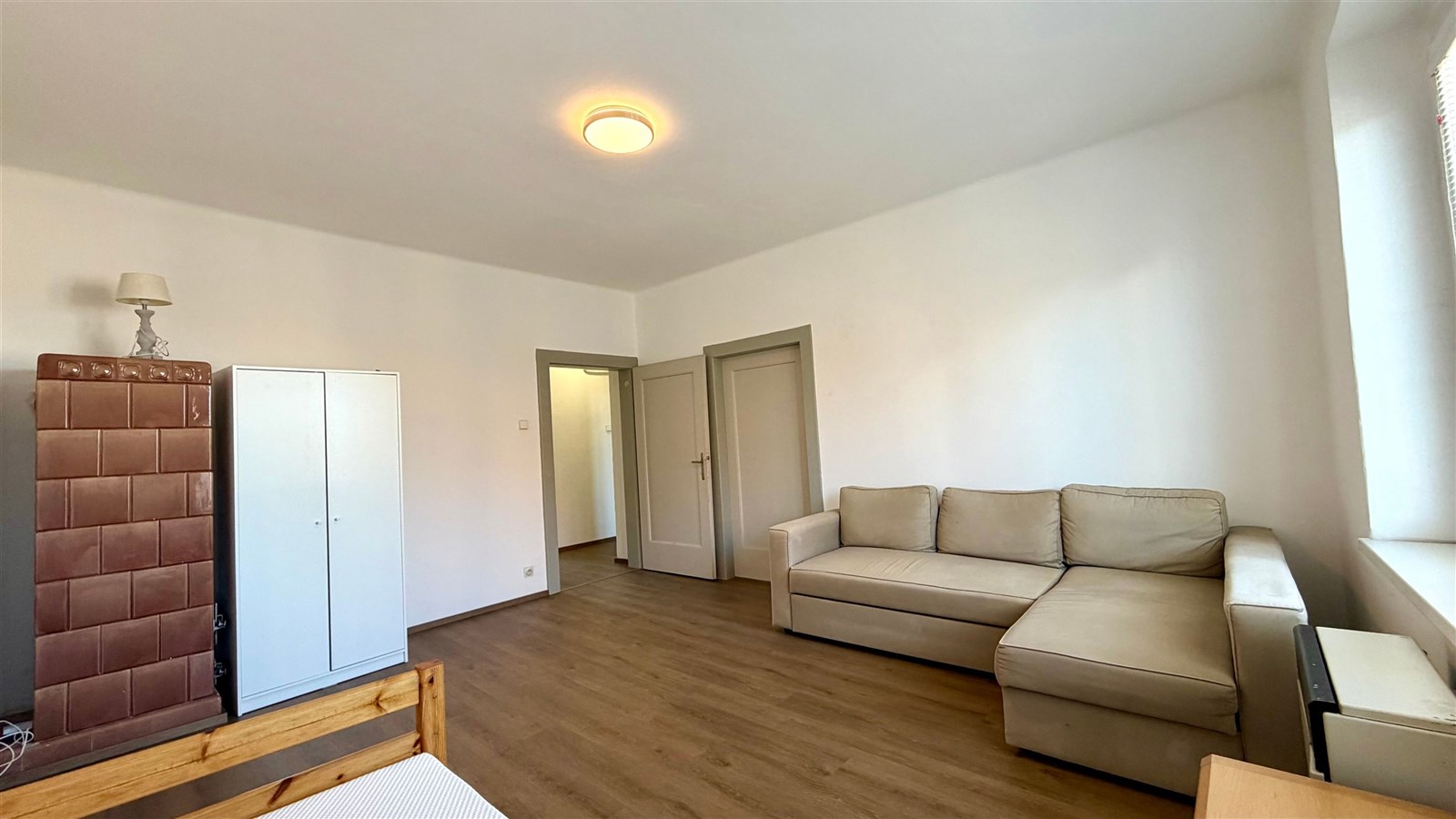 Světlý obývací pokoj s parketovou podlahou a pohodlnou sedací soupravou, doplněný vestavěnými skříněmi a moderním osvětlením.