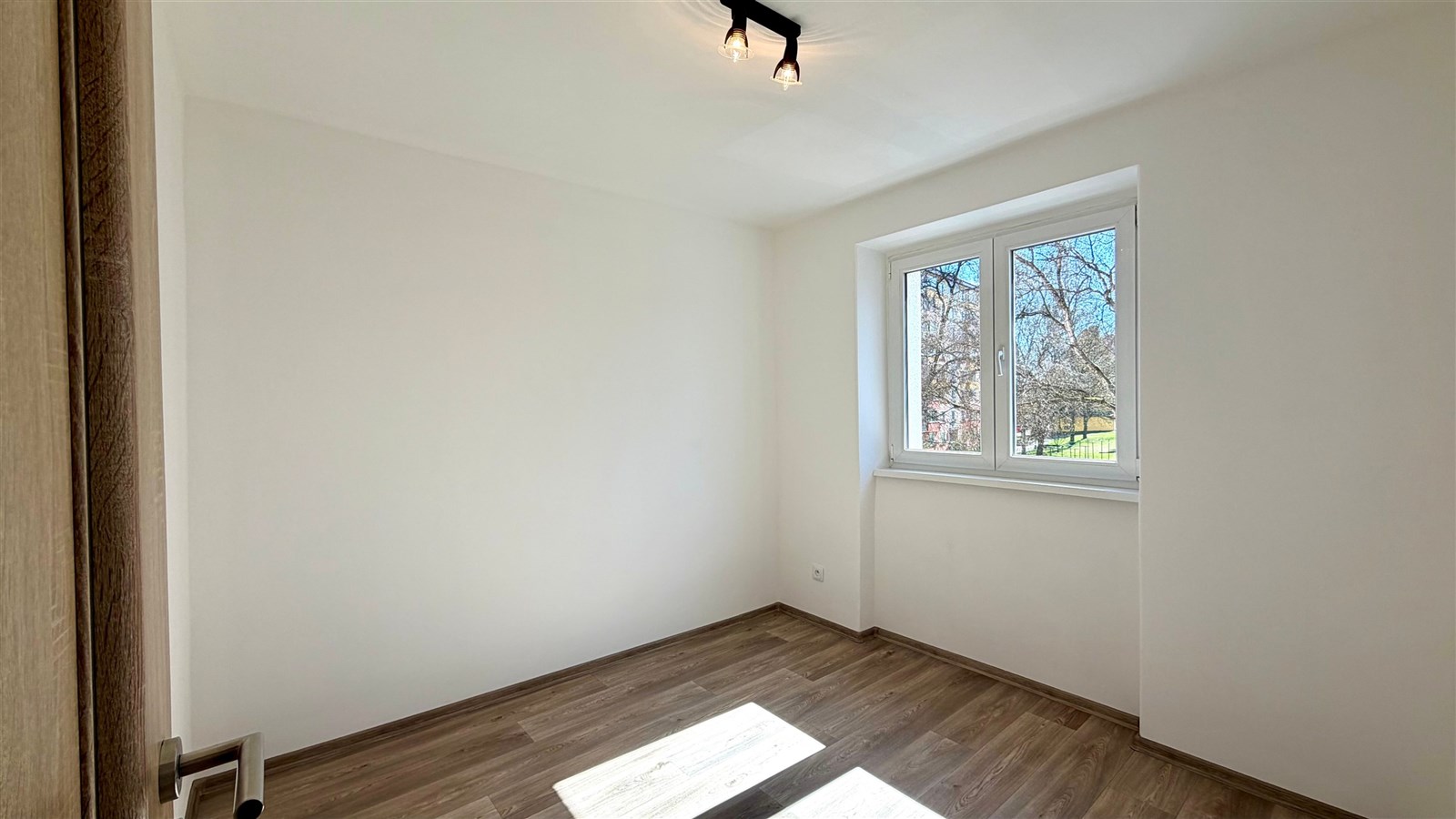 Prostorná ložnice s moderní laminátovou podlahou, velkými okny pro dostatek světla a novou výmalbou ve světlých tónech