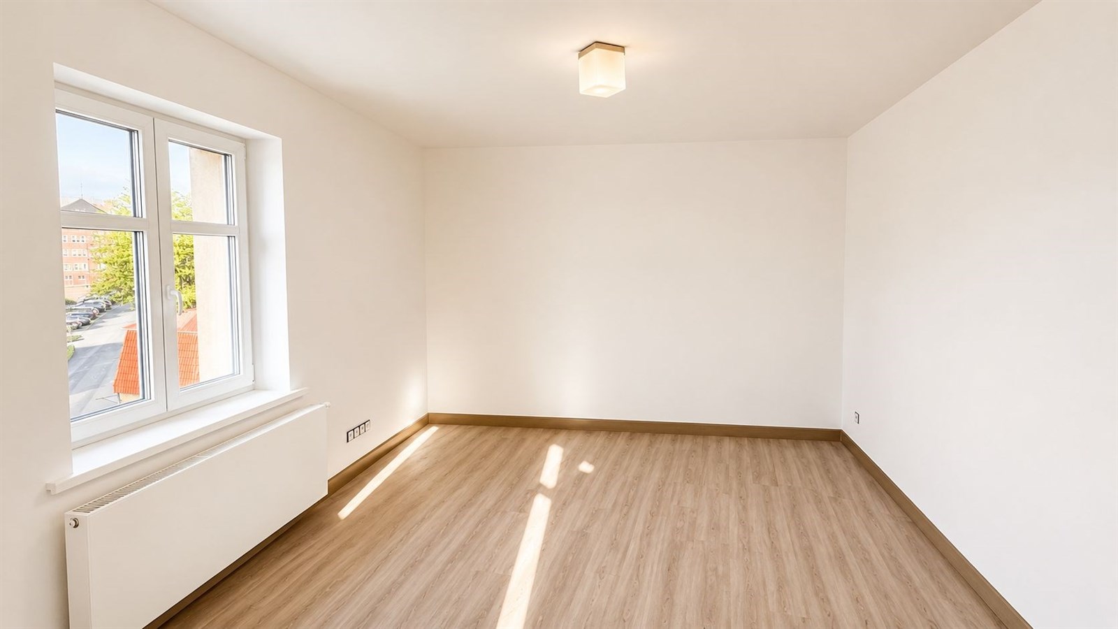 Prázdný pokoj s laminátovou podlahou, velkými okny a bílými stěnami, světelná moderní svítidlo na stropě, vhodný pro rekonstrukci nebo zařízení.