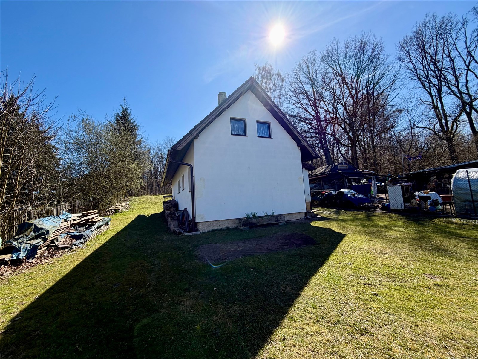 Rodinný dům s šikmou střechou, obklopený udržovanou zahradou, nacházející se na klidném místě blízko lesa.