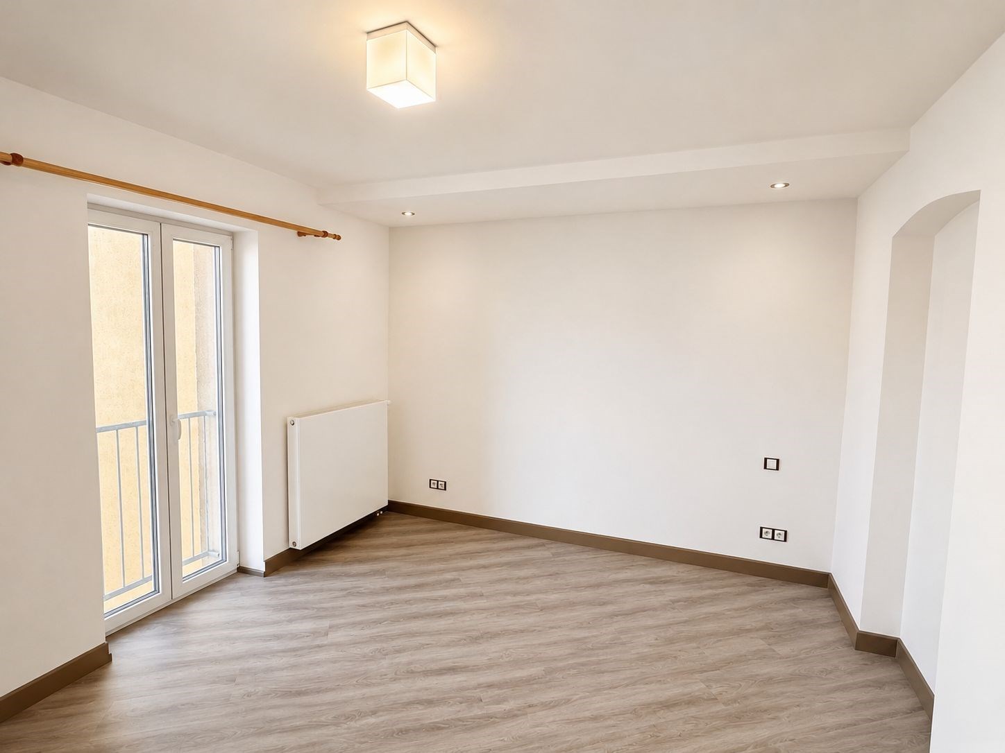 Světlý obývací pokoj s velkými okny, vinylová podlaha a moderní osvětlení, nově rekonstruovaný interiér s neutrálními barvami.