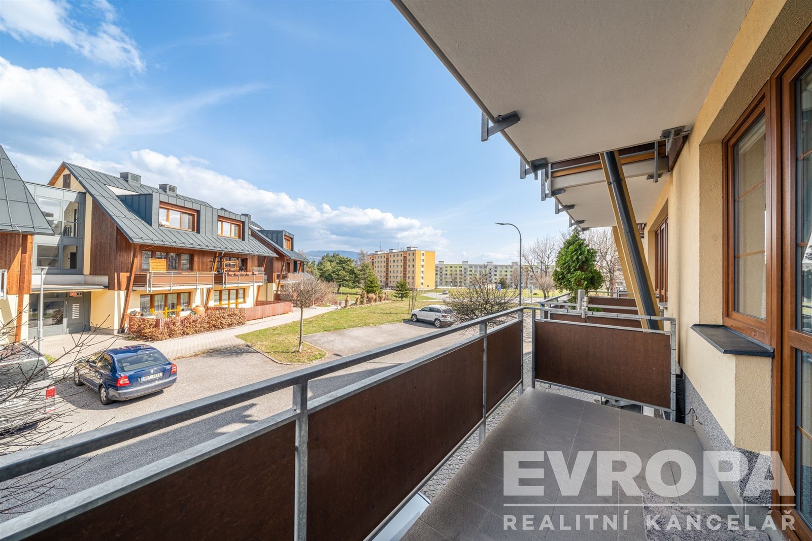 Prostorný balkon s dlažbou, nabízí výhled na moderní zástavbu, ideální pro relaxaci.