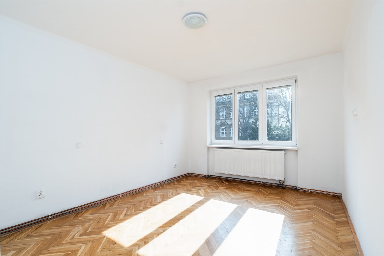 prázdná místnost s přirozené světlo, parketová podlaha, a radiátor