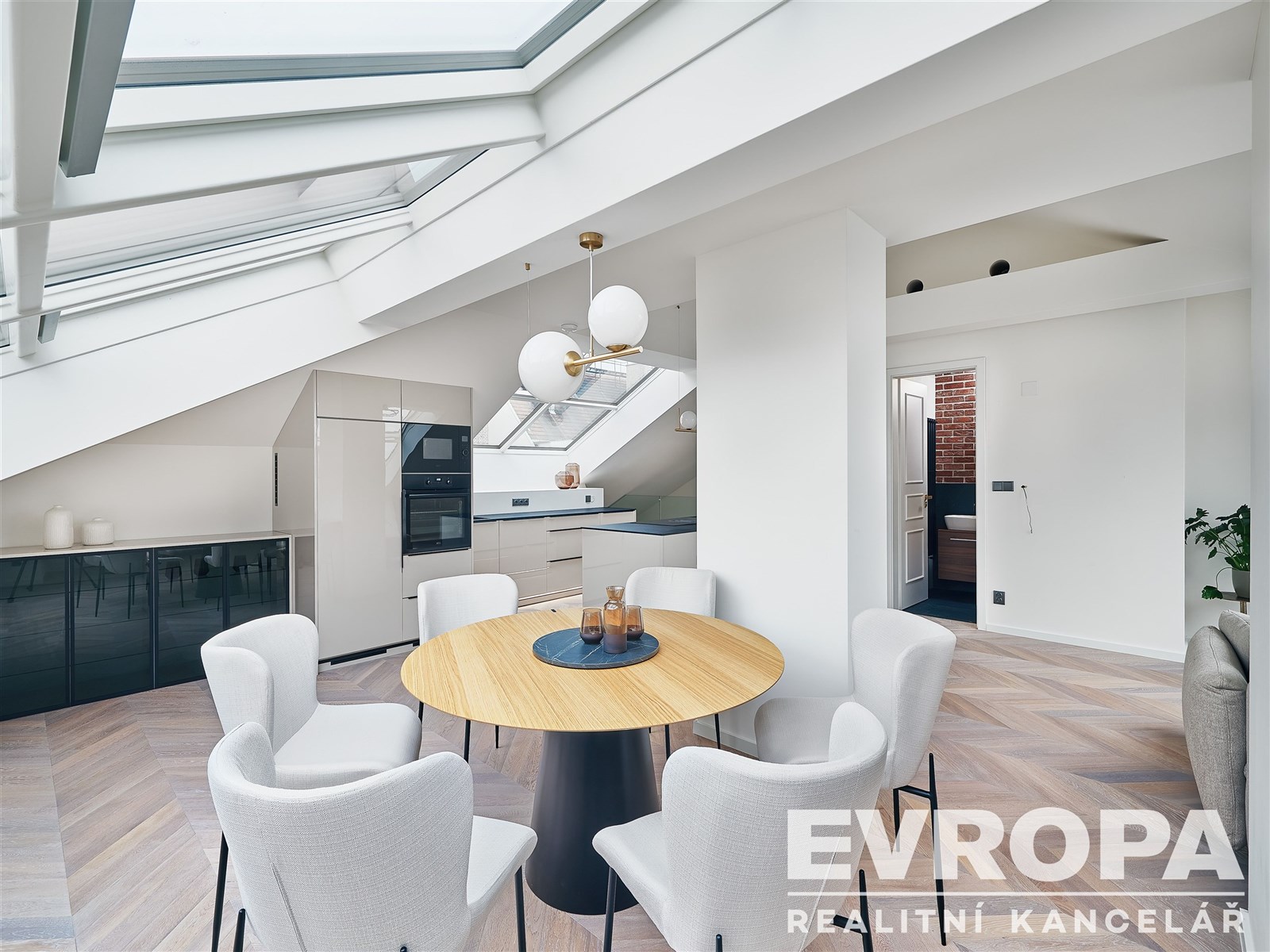 Světlá jídelna nabízí moderní design se světlým dřevem, velkými okny a parketovou podlahou, ideální pro pohodlné bydlení.
